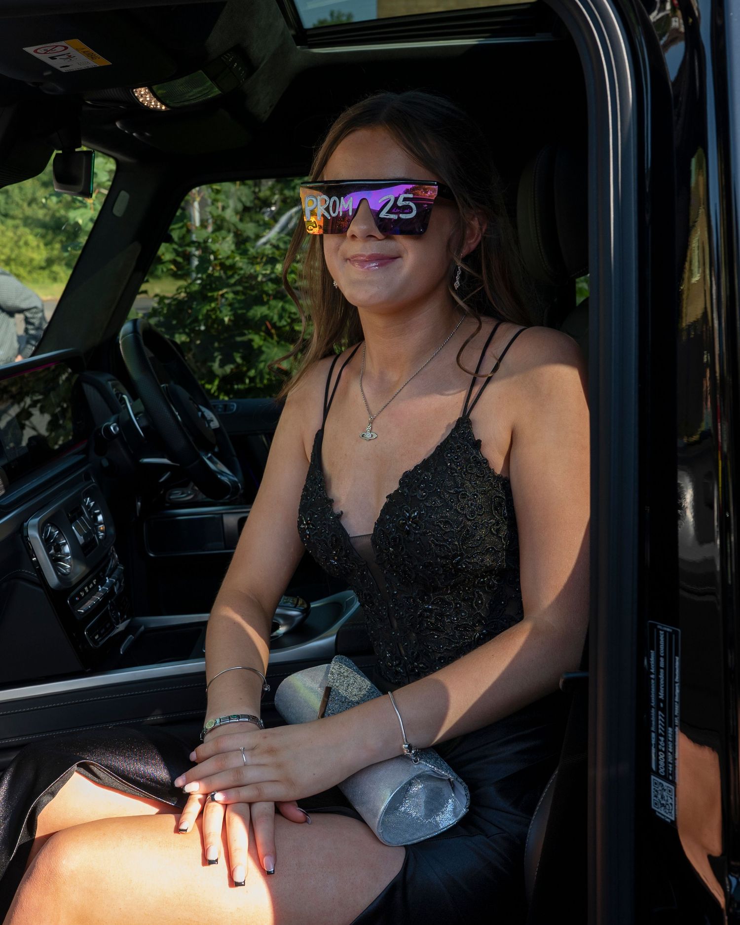 Person wearing a black lace dress sits in the driver's seat of a vehicle.