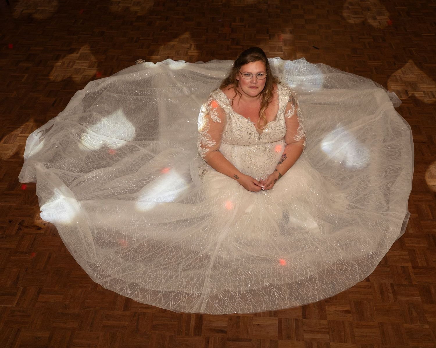 Wedding dress photos showing the full skirt spread out on a wooden floor.