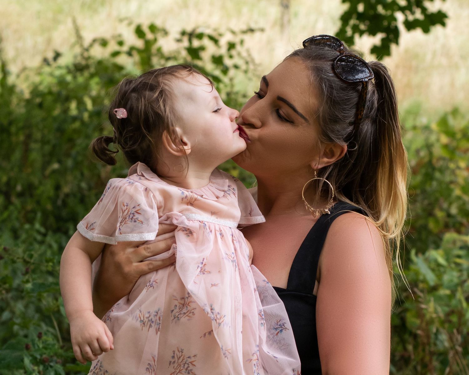 Sweet moment between parent and child in pink floral dress outdoors.