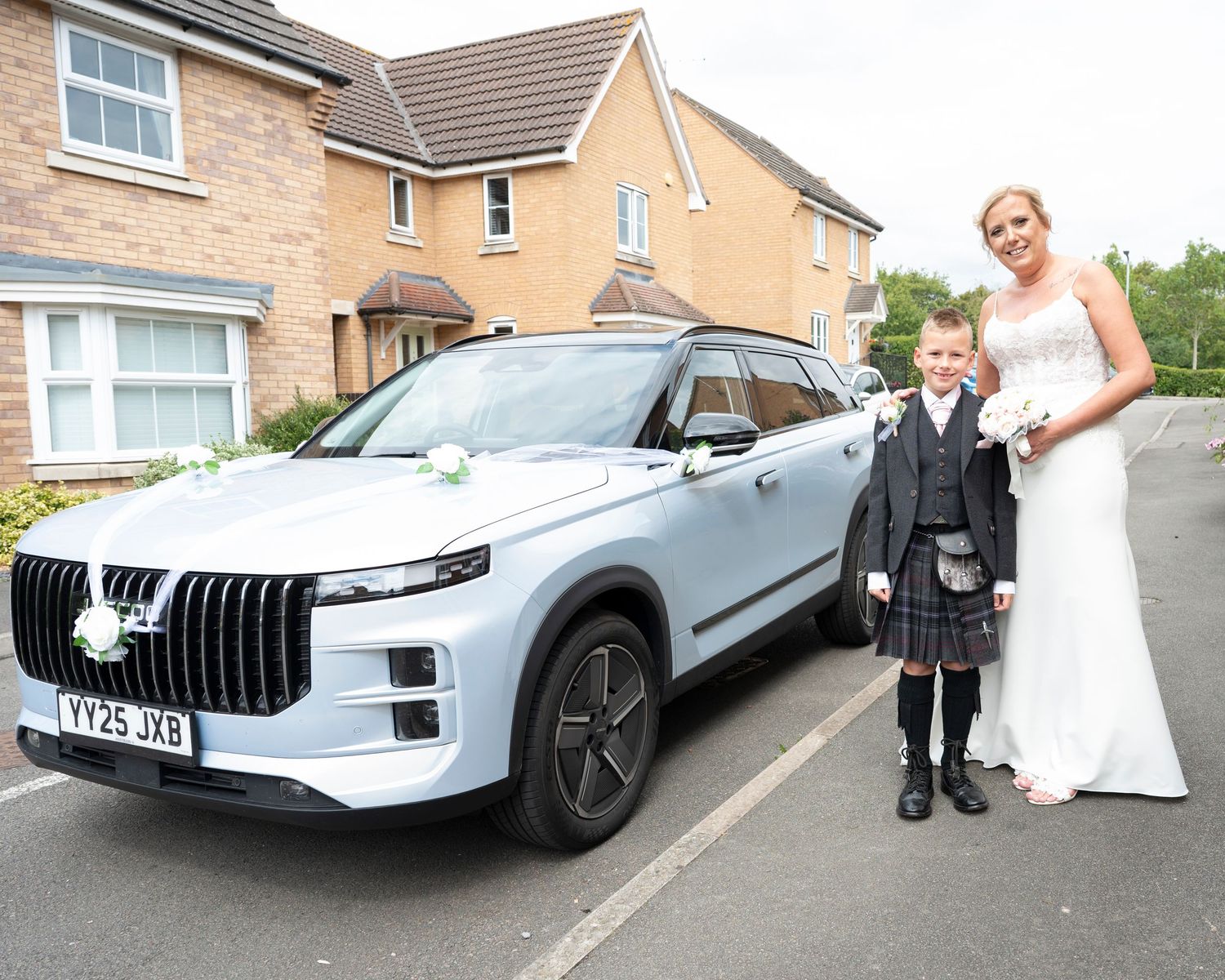 Wedding party photos with a luxury silver car parked outside brick houses.
