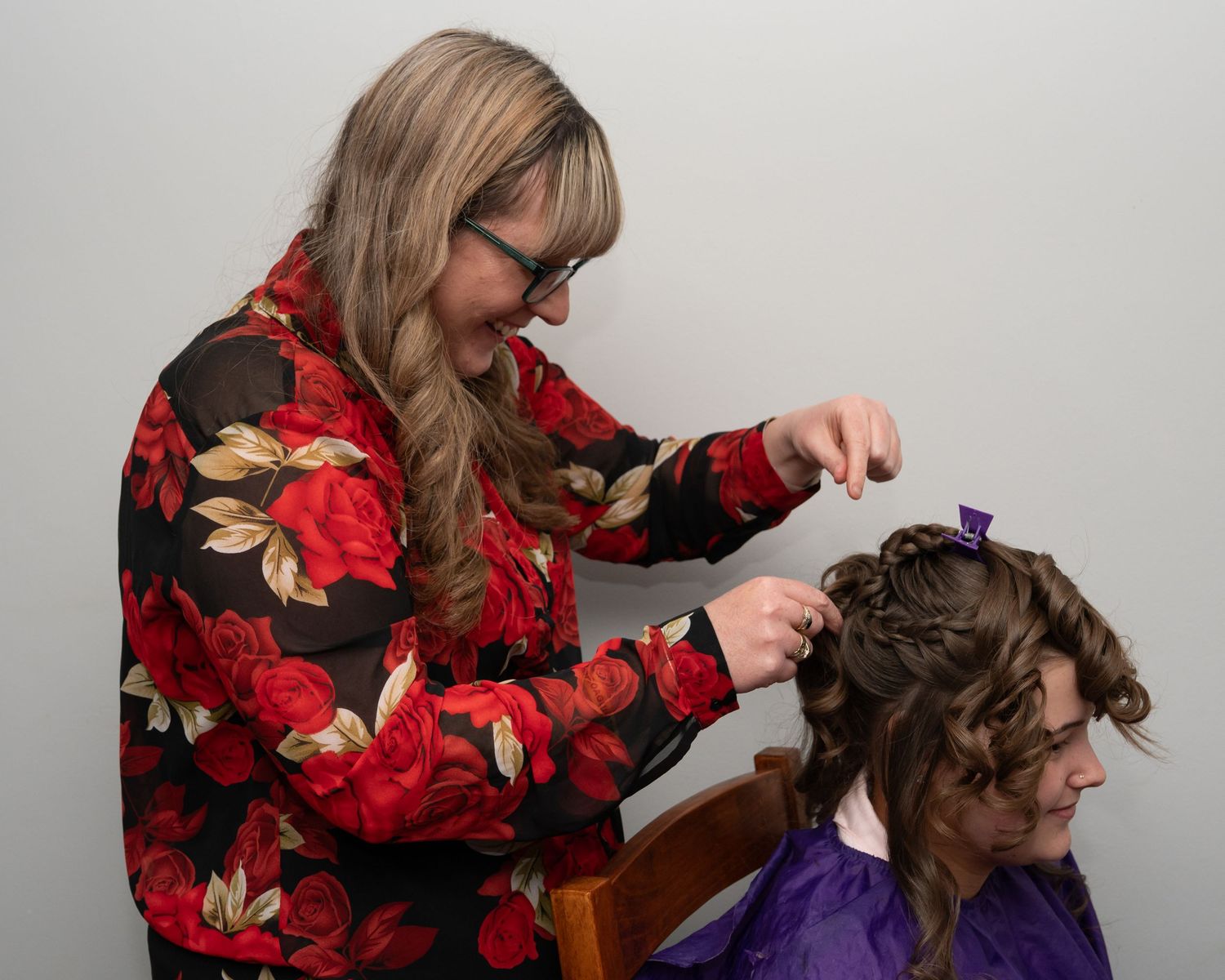 Hair styling session with floral print top and purple cape.