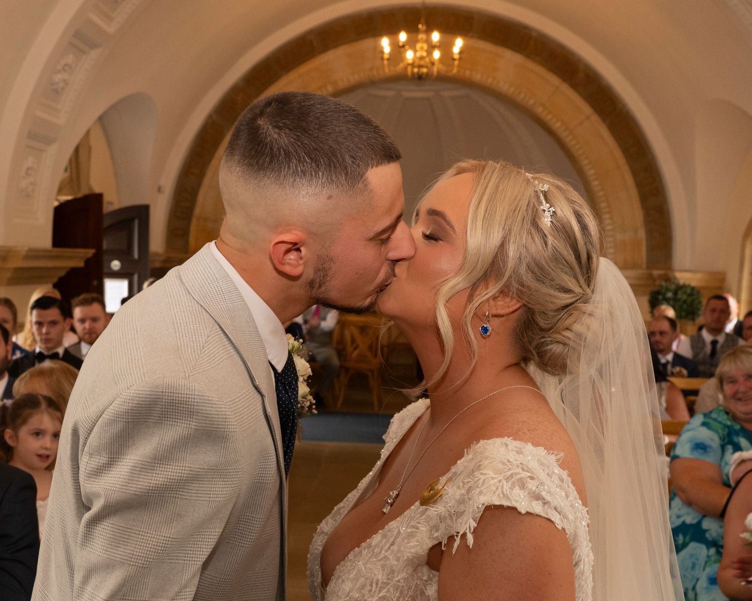 A romantic moment shared between newlyweds under an ornate church archway.