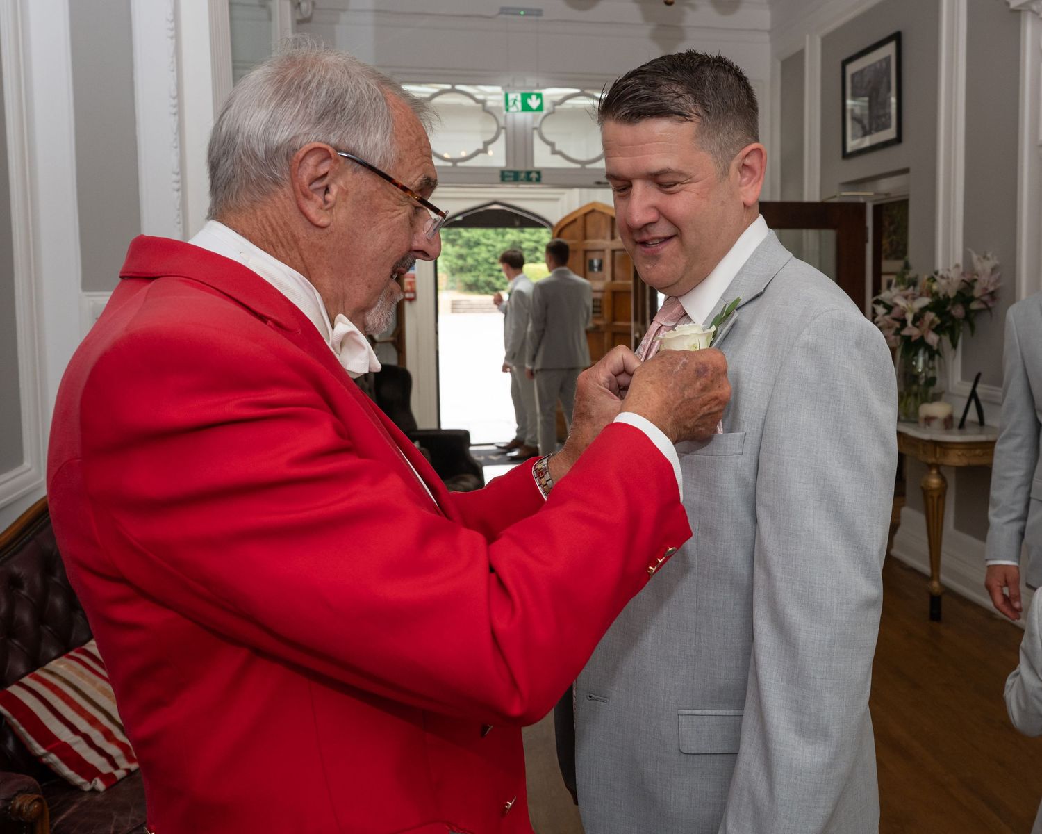 Series of candid moments showing men in formal attire embracing at an indoor venue.