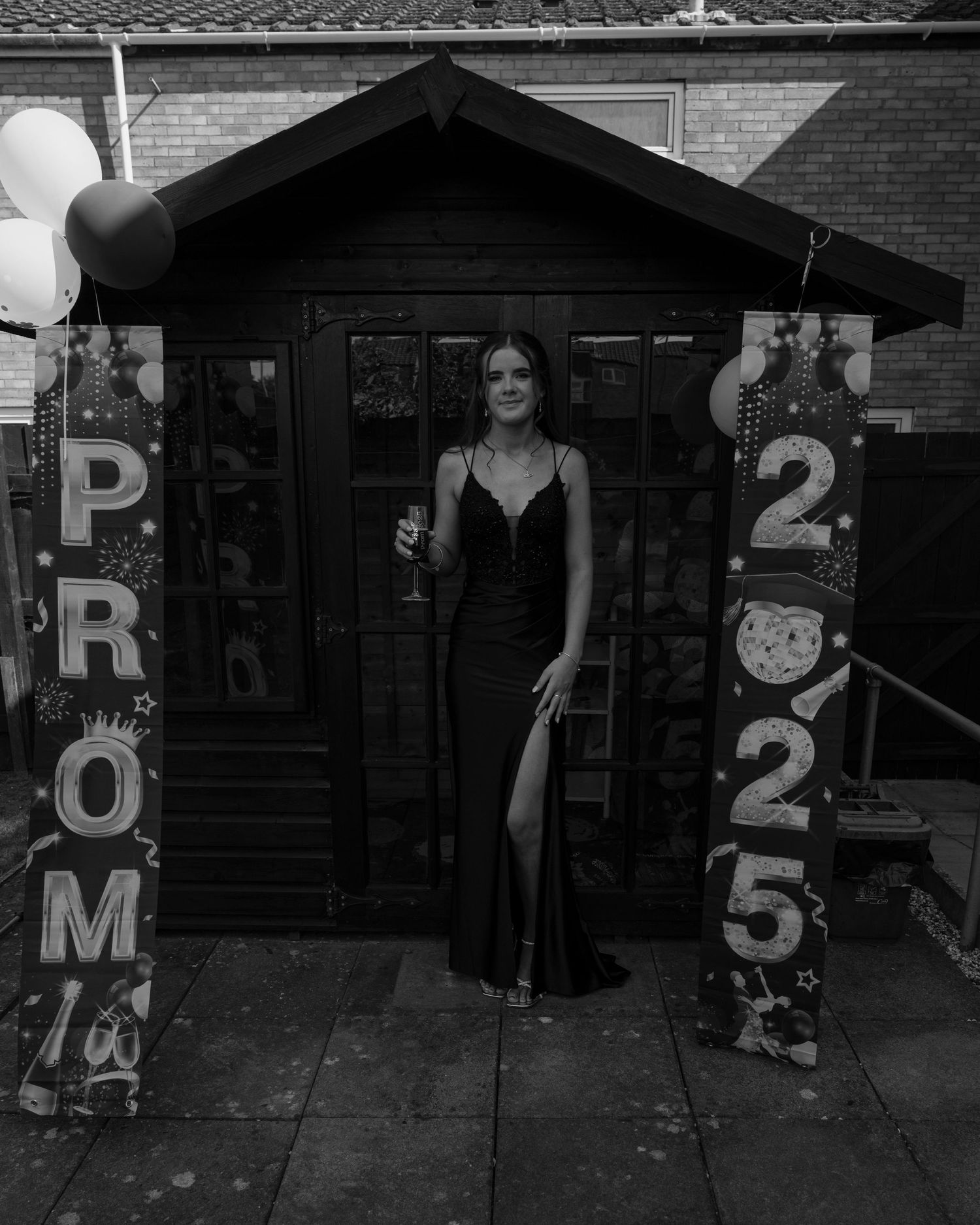 Black and white photo showing decorative prom signs and balloons outside a building.