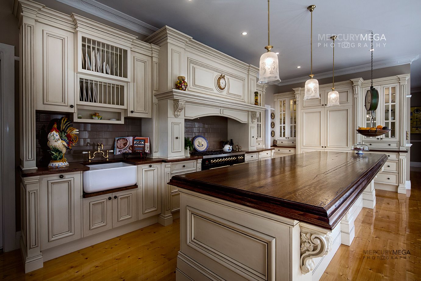 Elegant traditional kitchen with cream cabinets, dark wood island countertop, pendant lights, and hardwood floors.