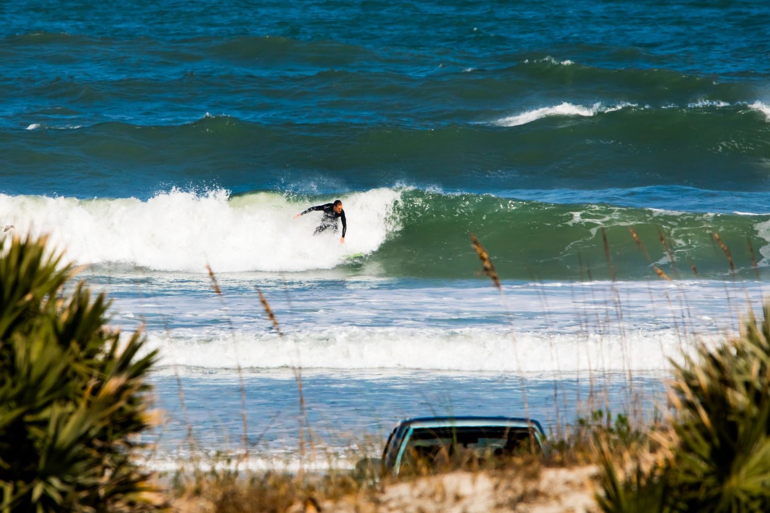 Surfer riding a wave photographed from shore in Ponce Inlet Florida. Goodreau.co