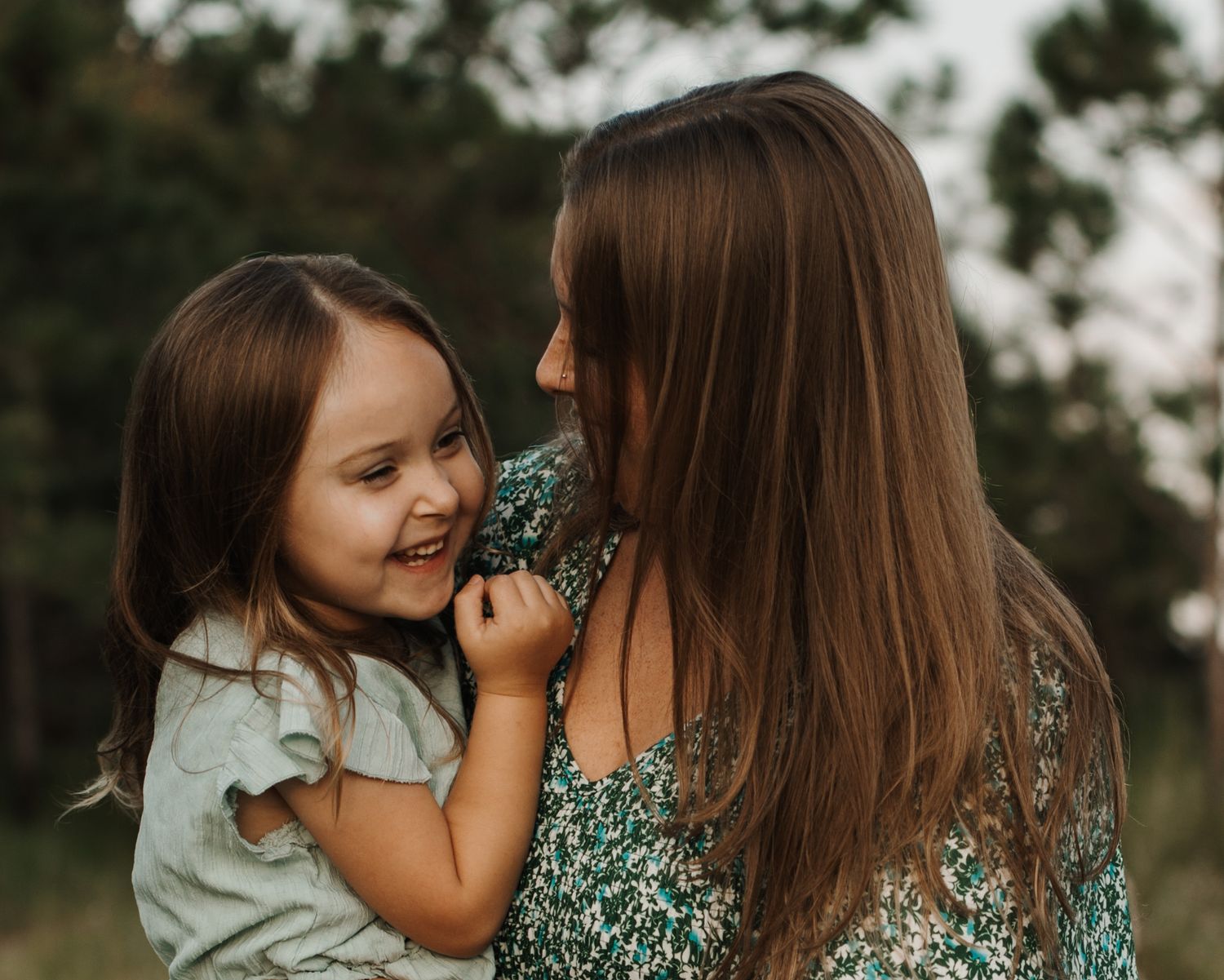 Mother and young daughter laughing together during an outdoor lifestyle photography session. Goodreau.co