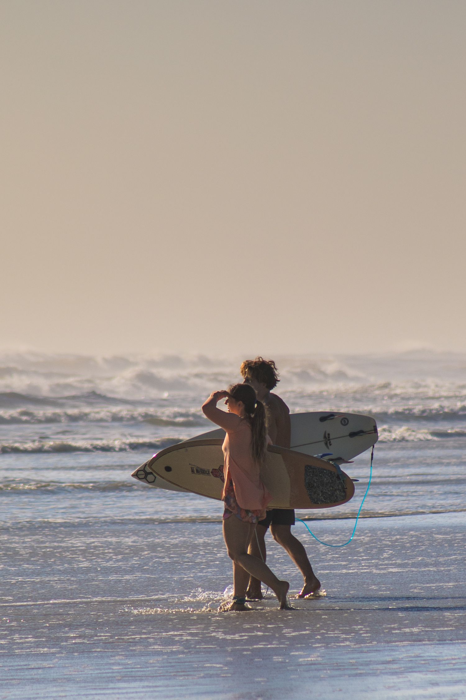 Surfer carrying surfboards toward the beach. Goodreau.co