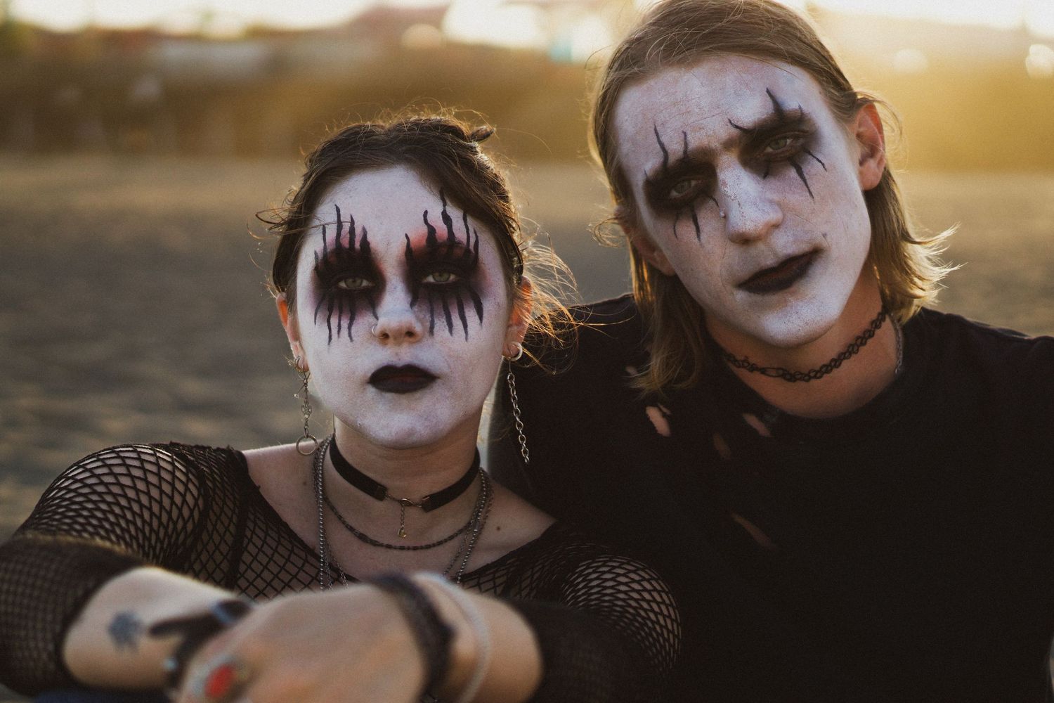 Editorial portrait of two people wearing dramatic black and white gothic makeup outdoors at golden hour. Goodreau.co