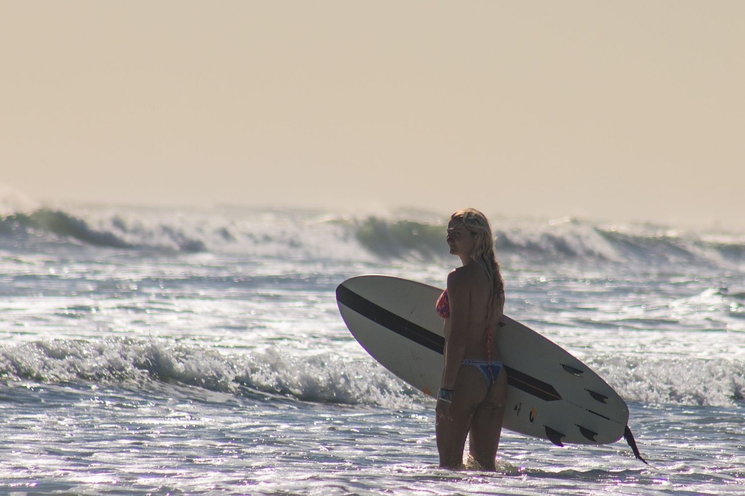 Female surfer holding a surfboard in the ocean during a Florida surf photography session. Goodreau.co