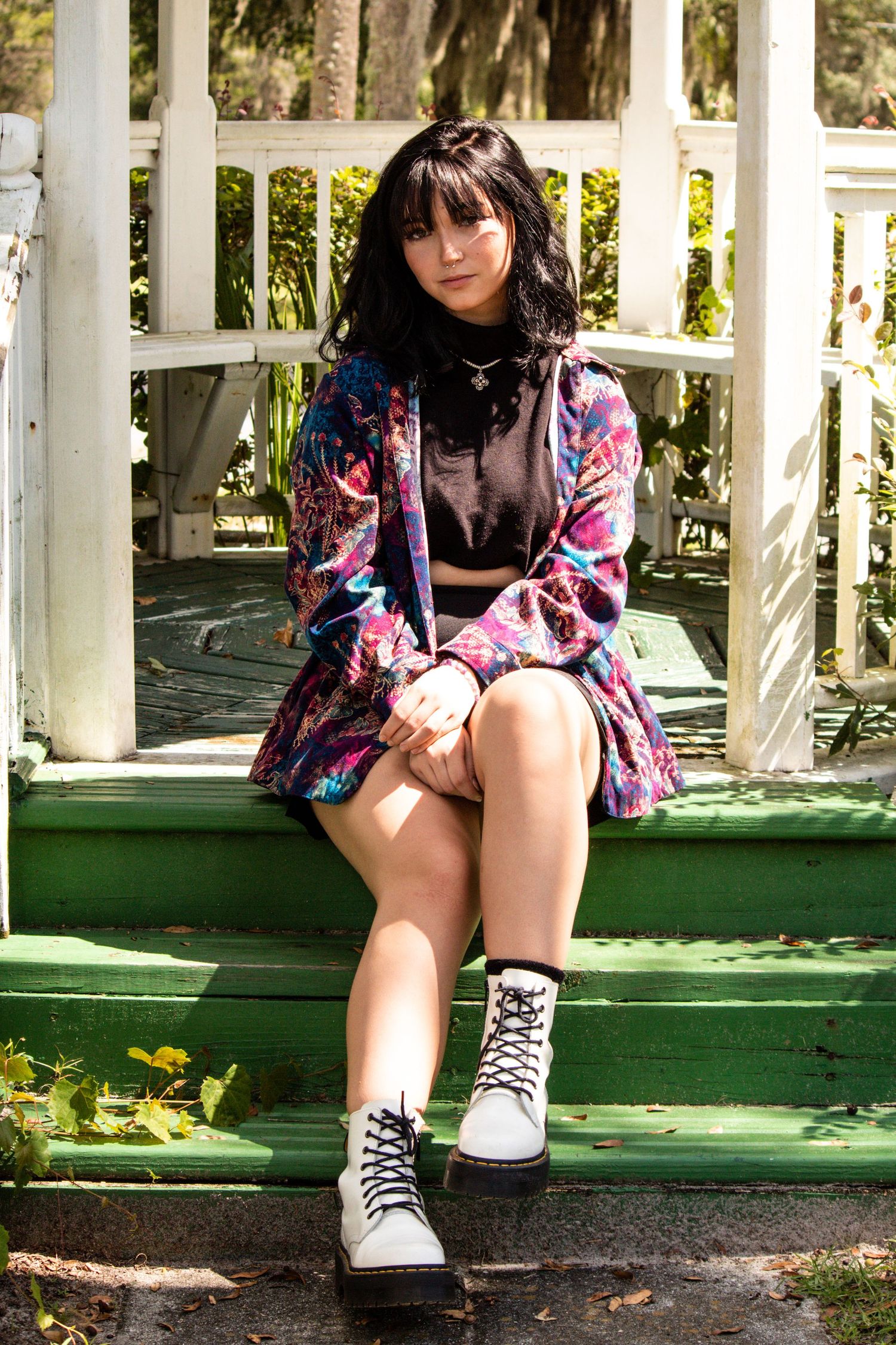 Editorial portrait of a woman in colorful clothing and white boots sitting on outdoor steps. Goodreau.co