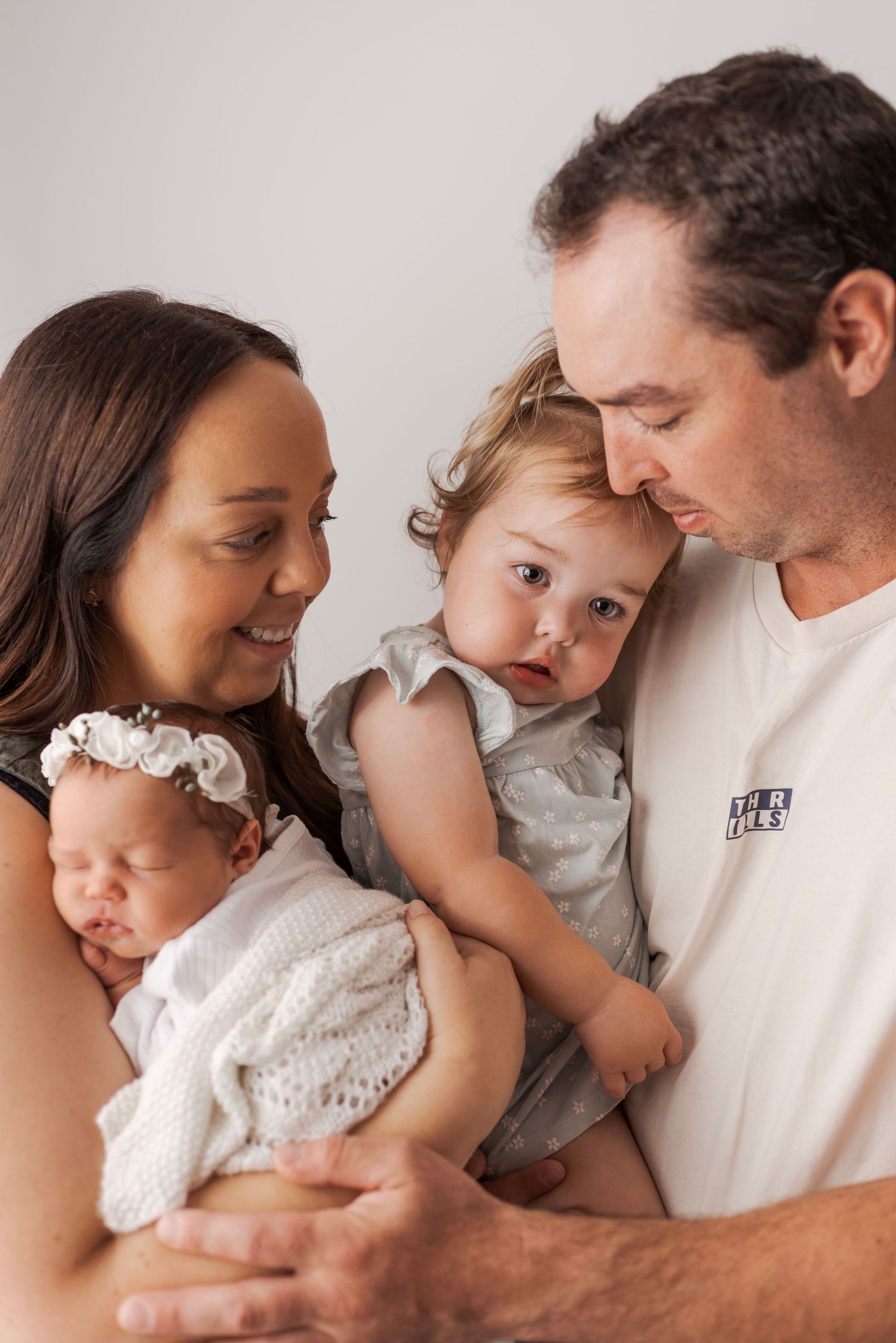 Happy family of four with newborn baby girl and toddler posing for portrait photo.
