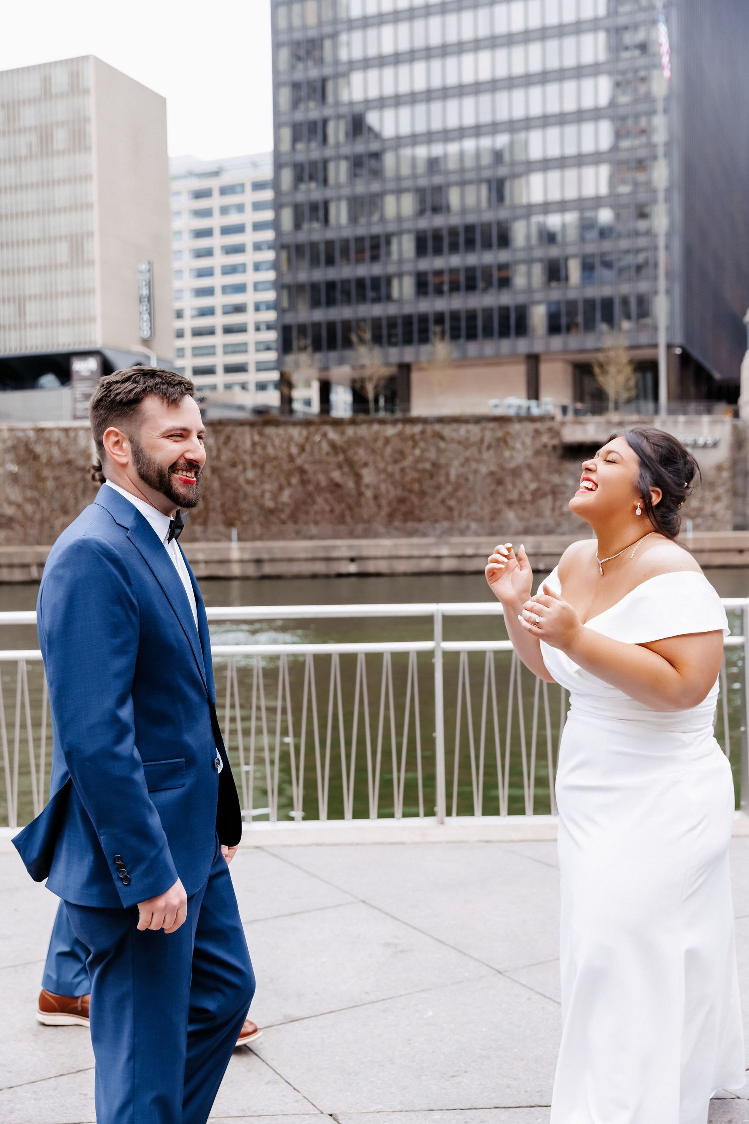 Joyful bride and groom share a laugh in wedding attire along the Chicago Riverwalk waterfront.