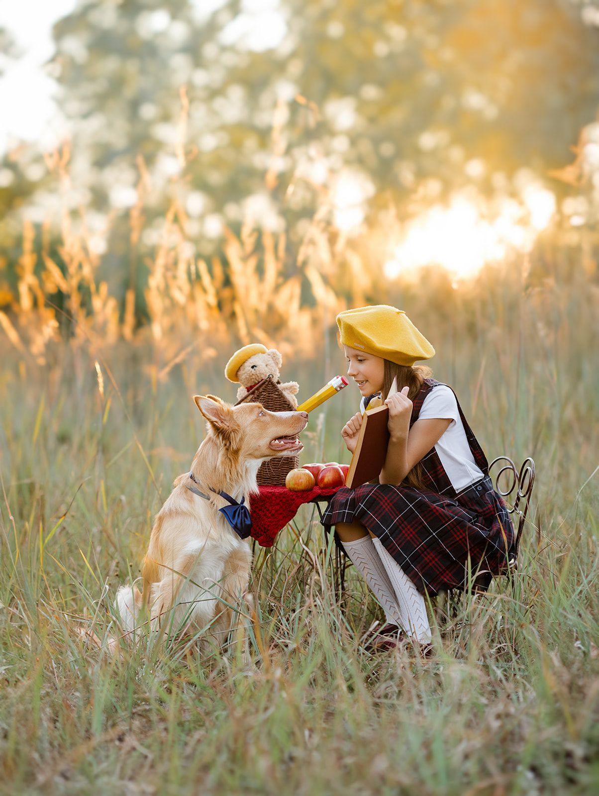 A young girl in a yellow beret feeds her German Shepherd dog in a golden sunlit field at sunset.