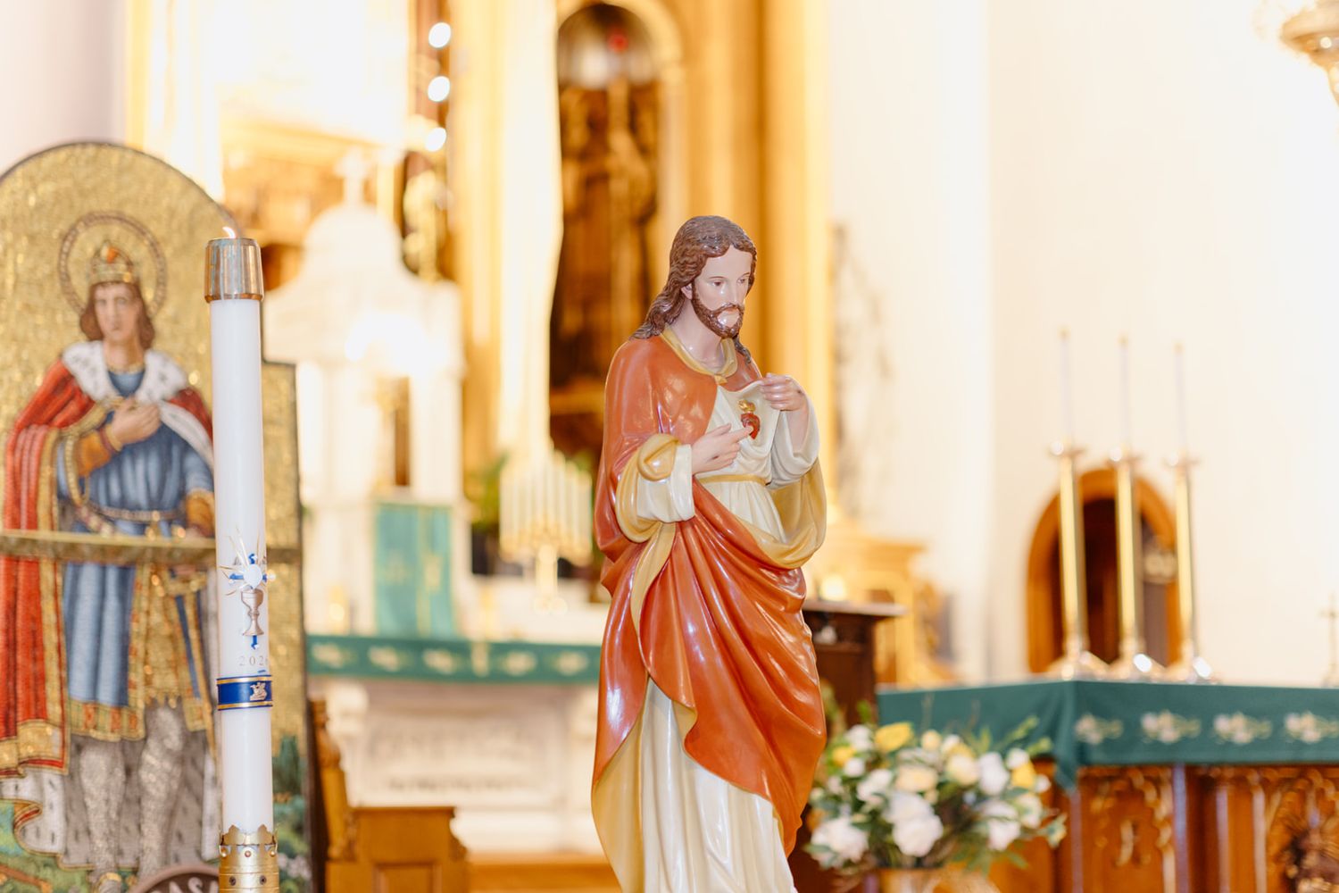 Colorful statue of Jesus Christ displayed inside a Catholic church near the altar with religious icons.