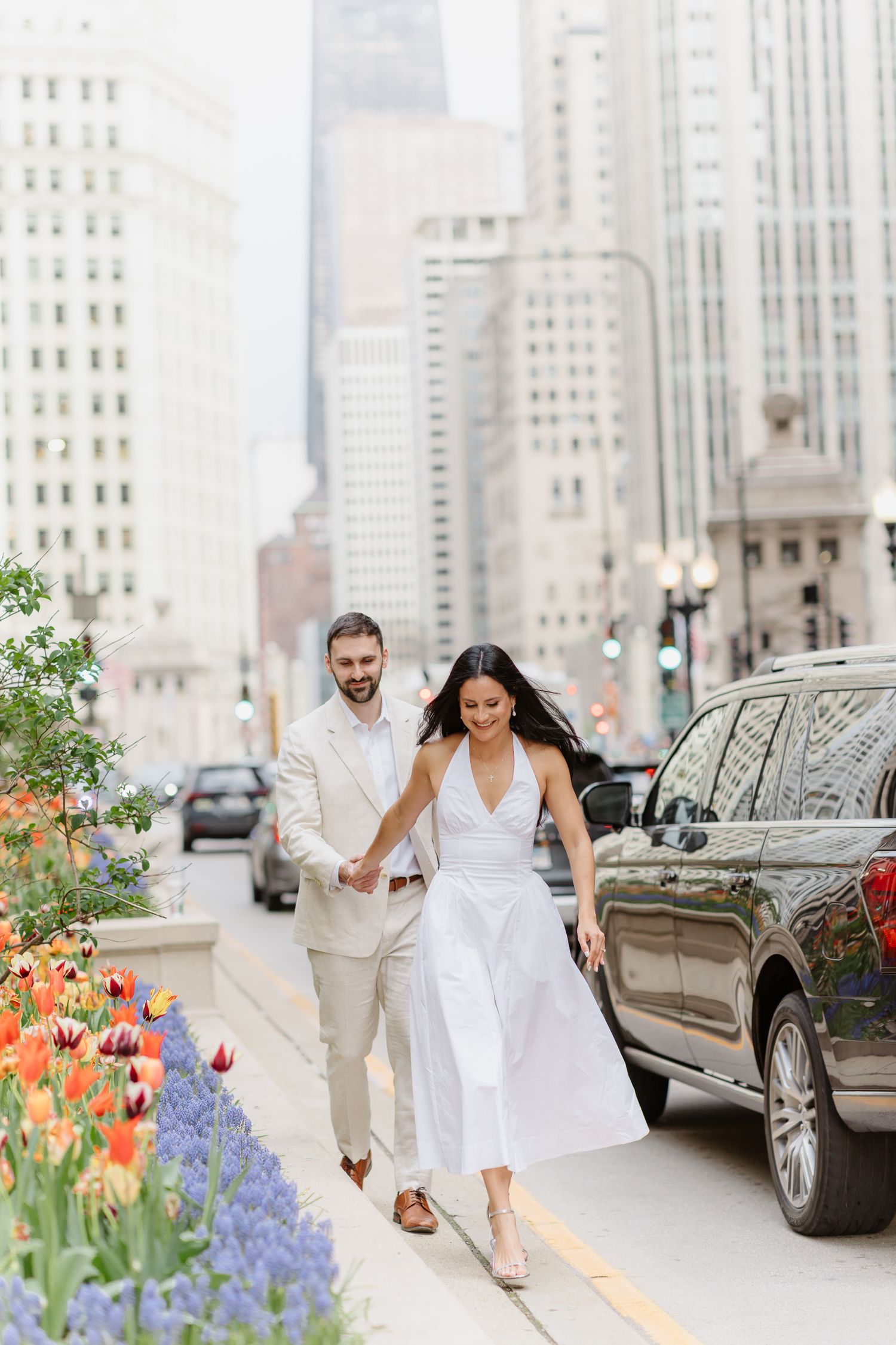 Couple walks hand-in-hand along Chicago's Michigan Avenue median beside colorful spring tulip gardens.