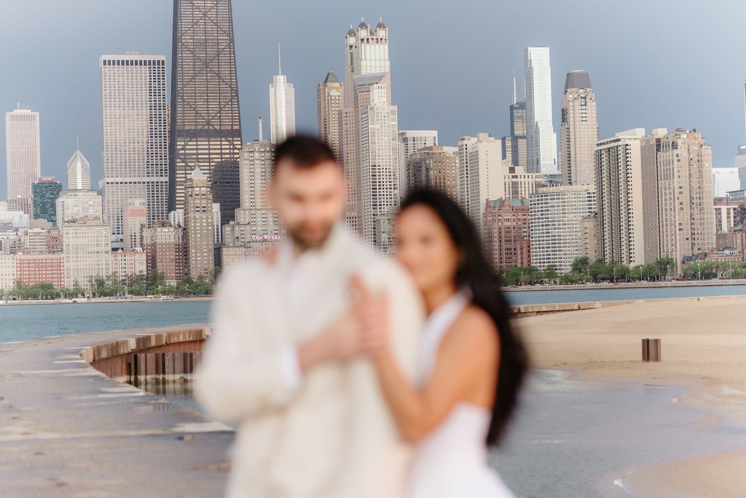Bride and groom share romantic moment with blurred Chicago cityscape behind them.