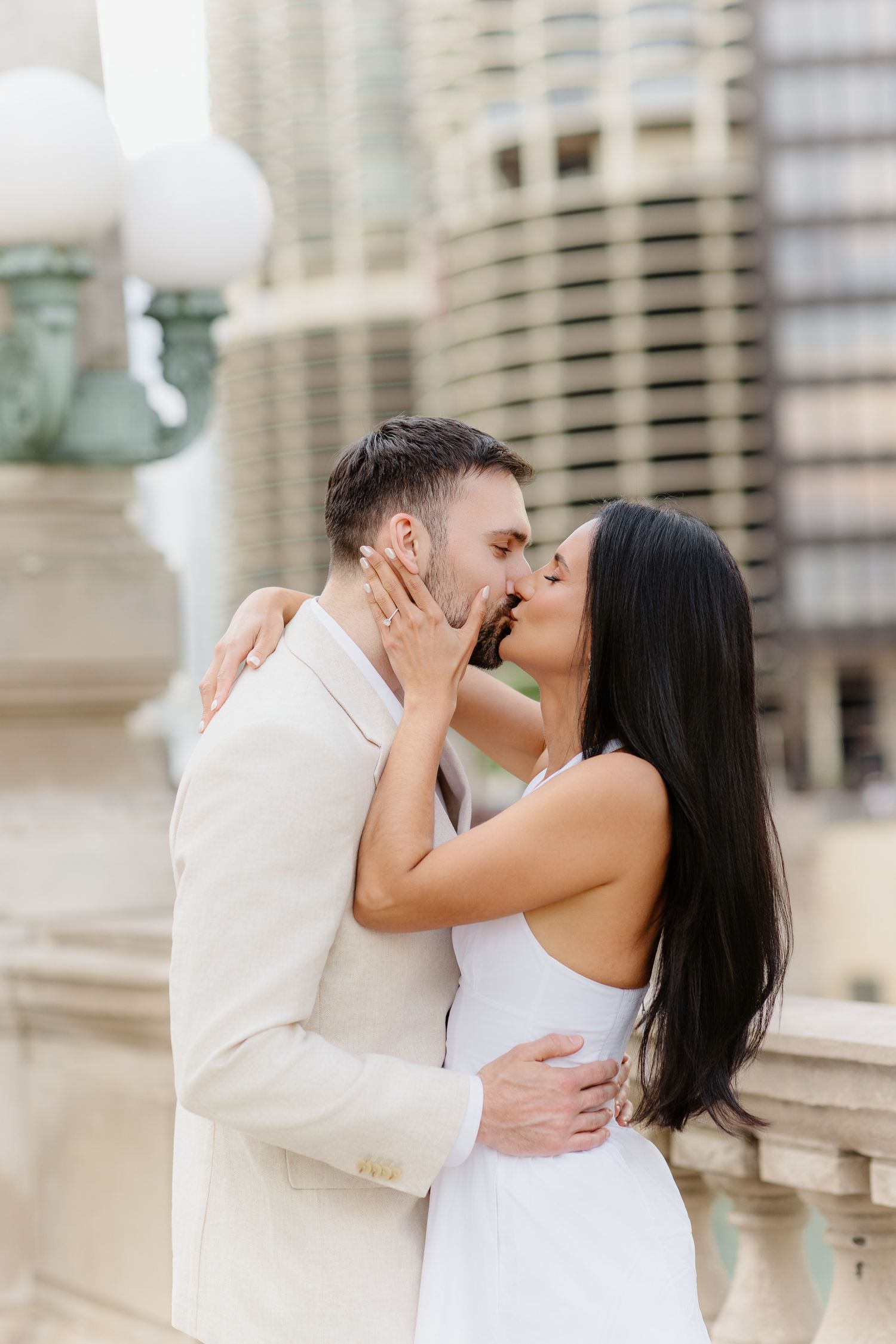 Couple shares a romantic kiss during urban engagement session with Chicago skyscrapers in the background.