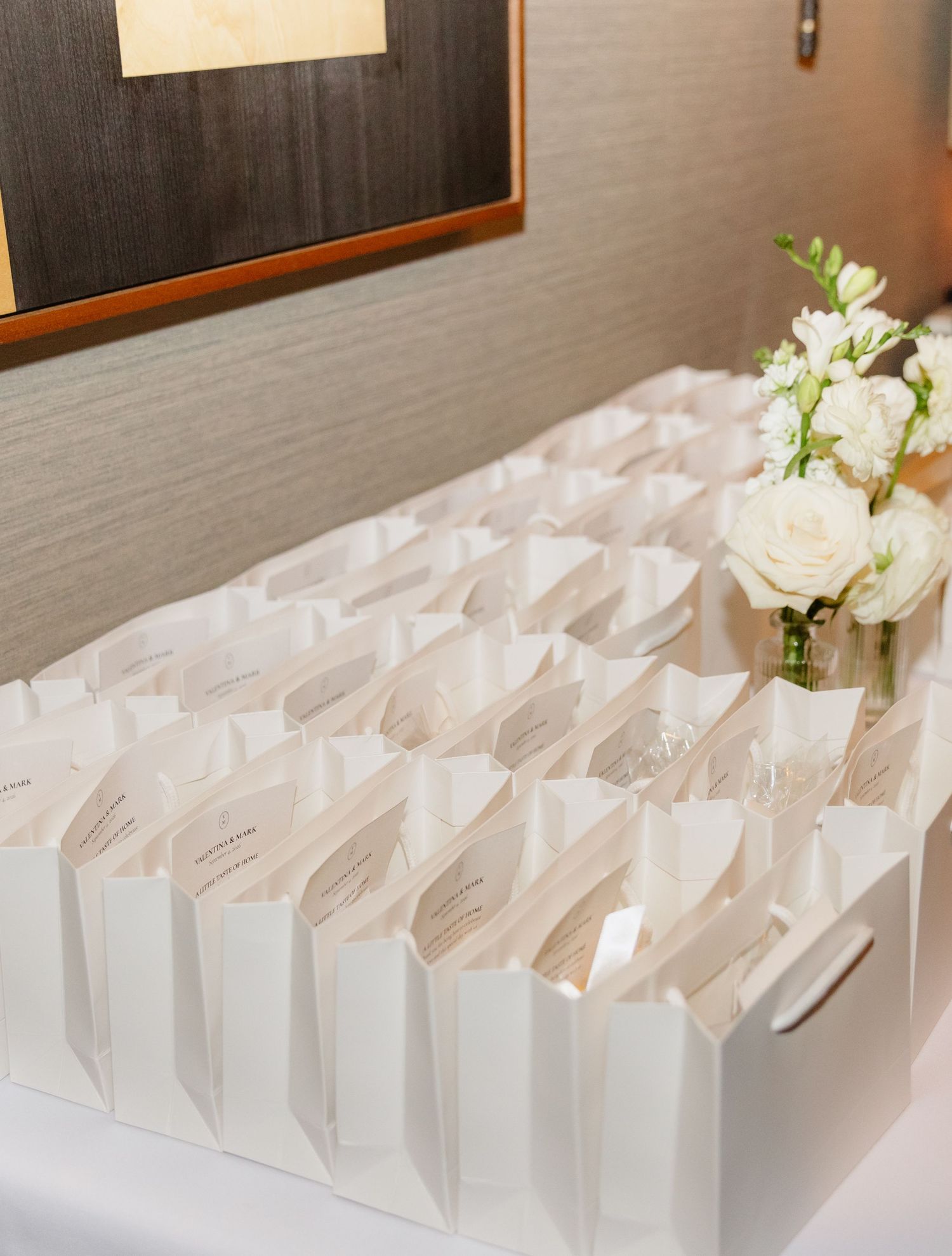 Neatly arranged white escort card holders with ribbon accents displayed on a table with white floral centerpiece.