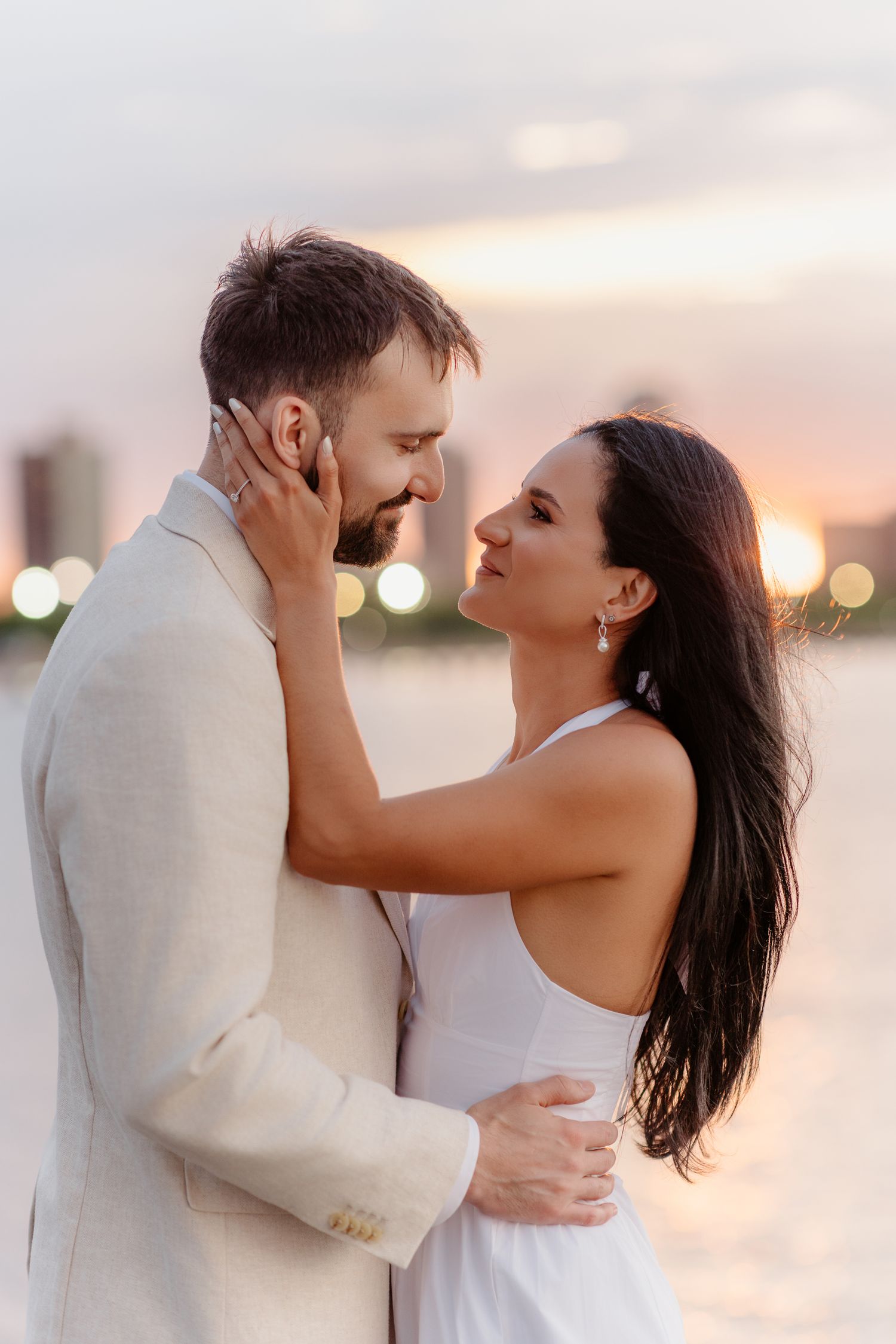 Couple gazing at each other tenderly during romantic sunset engagement session.