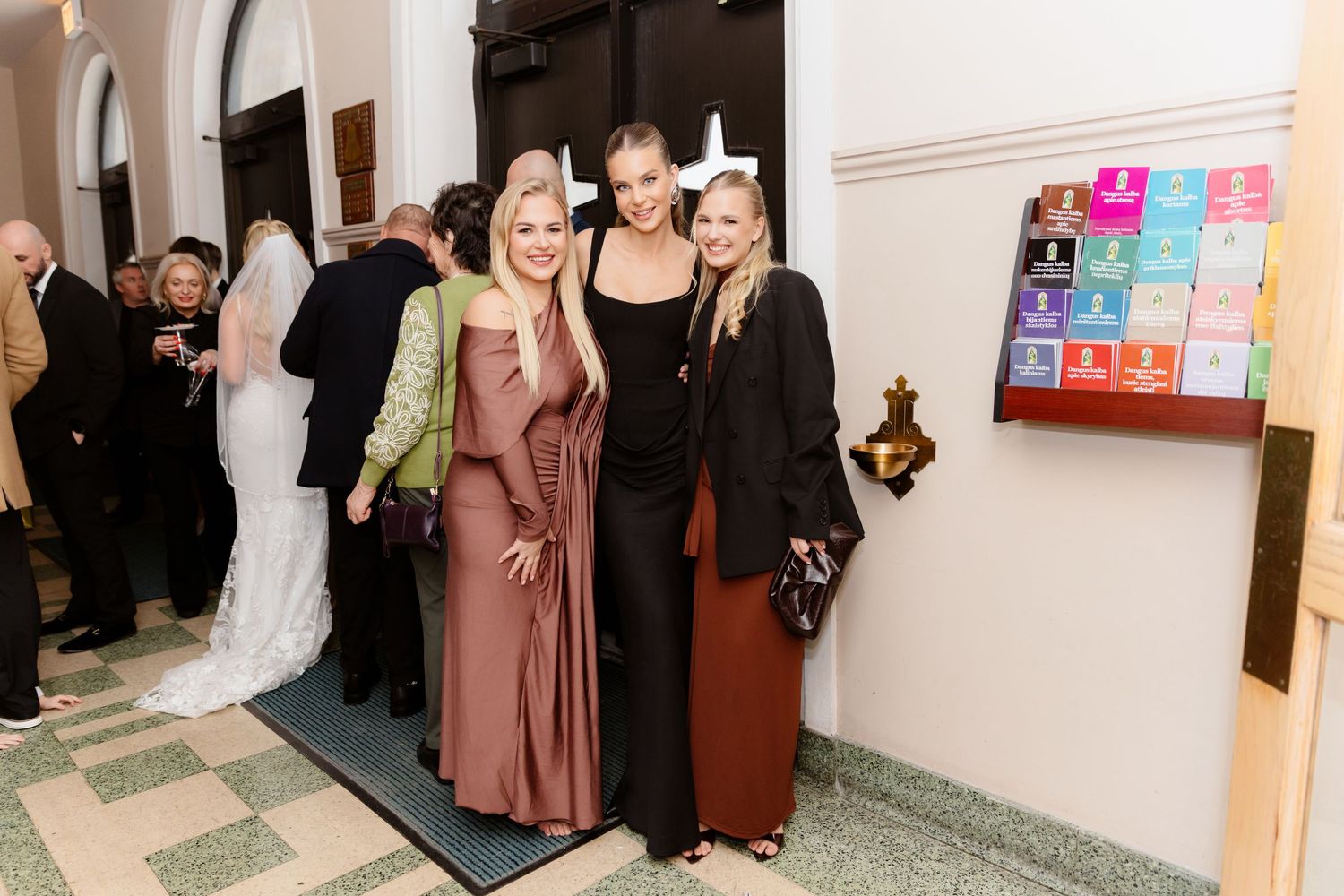 Three elegant women posing together at formal wedding reception venue.