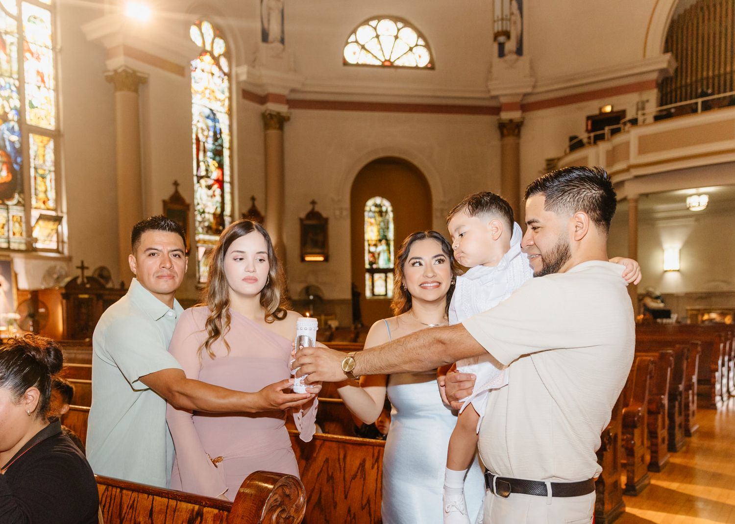 Group of family members sharing a baptism candle at a church christening celebration.