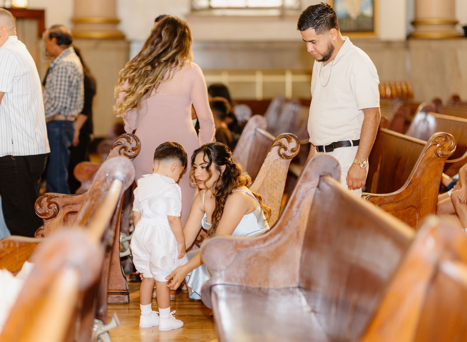 Family gathering in church pews during a baptism ceremony, with children and adults dressed in formal attire.