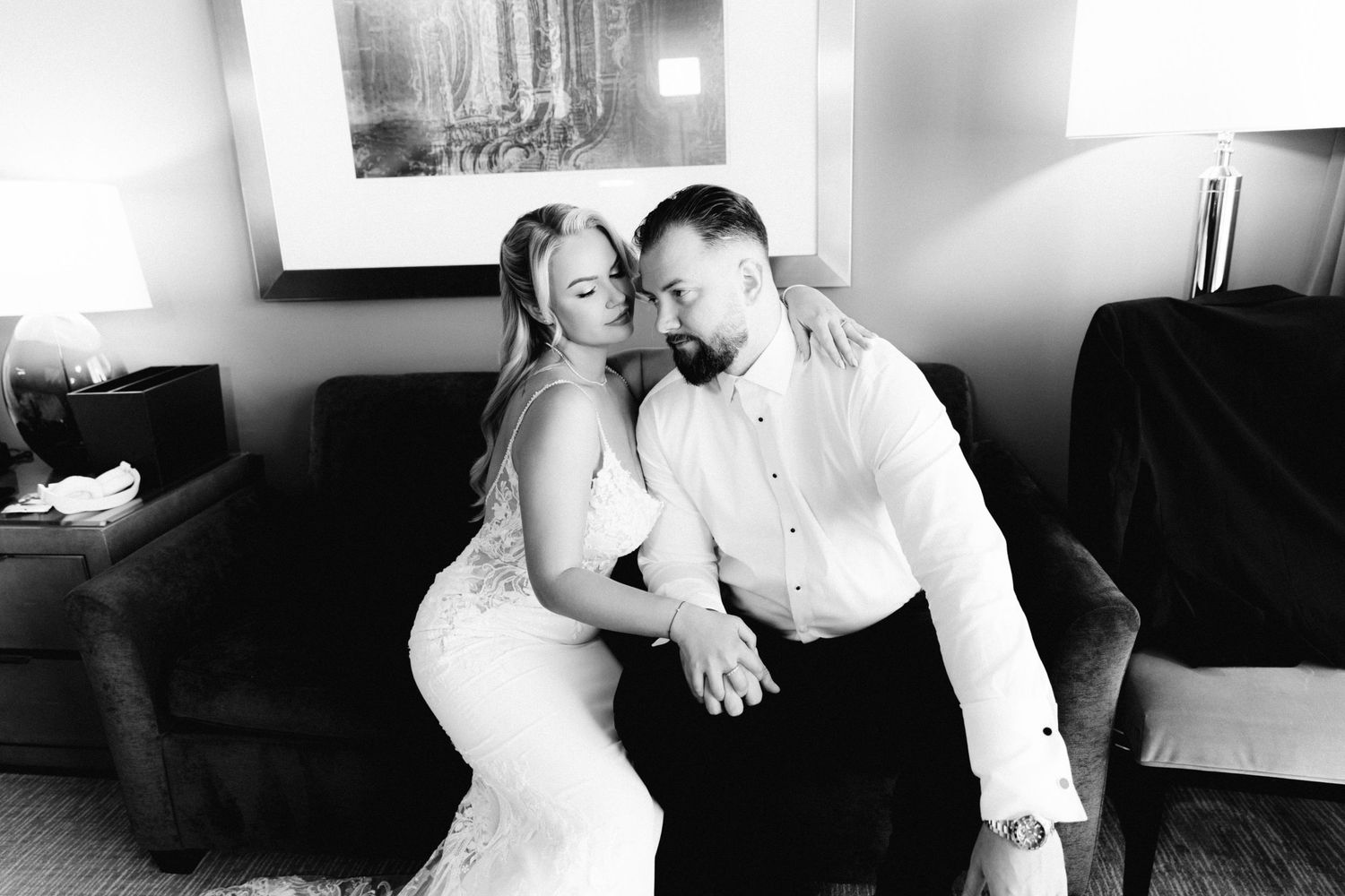 Black and white photo of bride and groom sharing a tender romantic moment seated together.