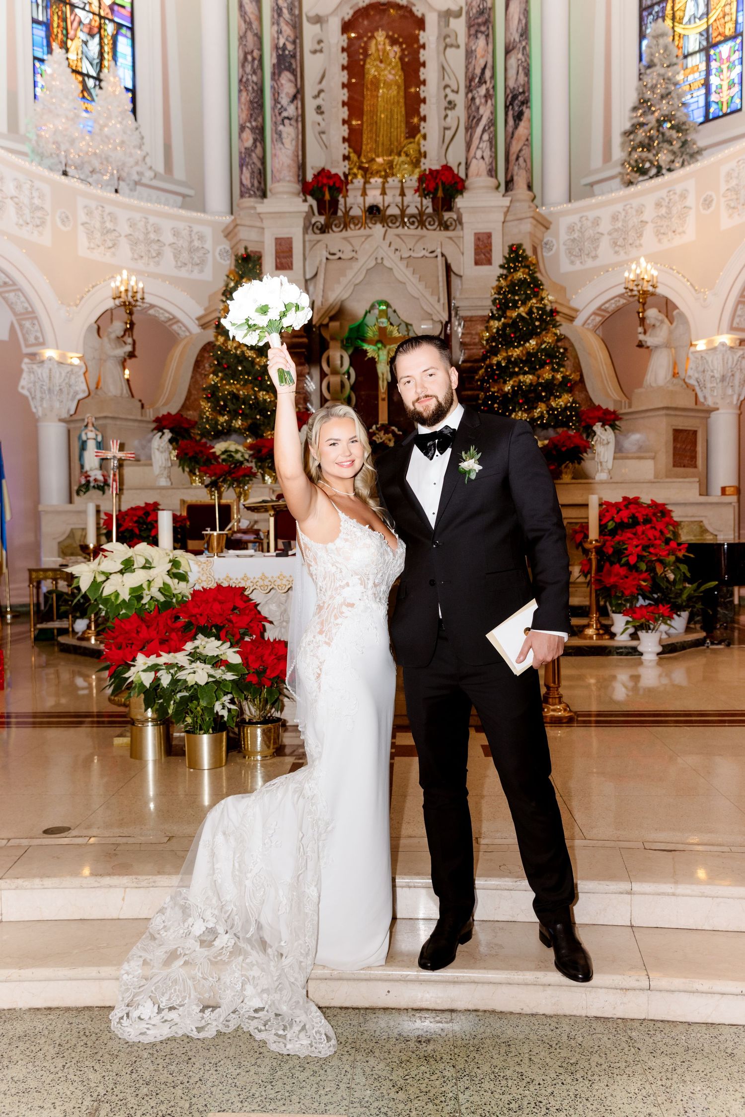 Bride and groom celebrating at the altar of a Christmas-decorated church after their wedding ceremony.
