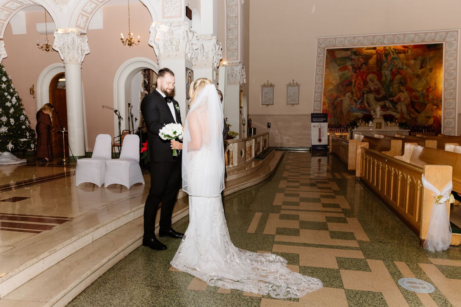 Bride and groom share romantic first look moment in ornate church lobby with marble floors.