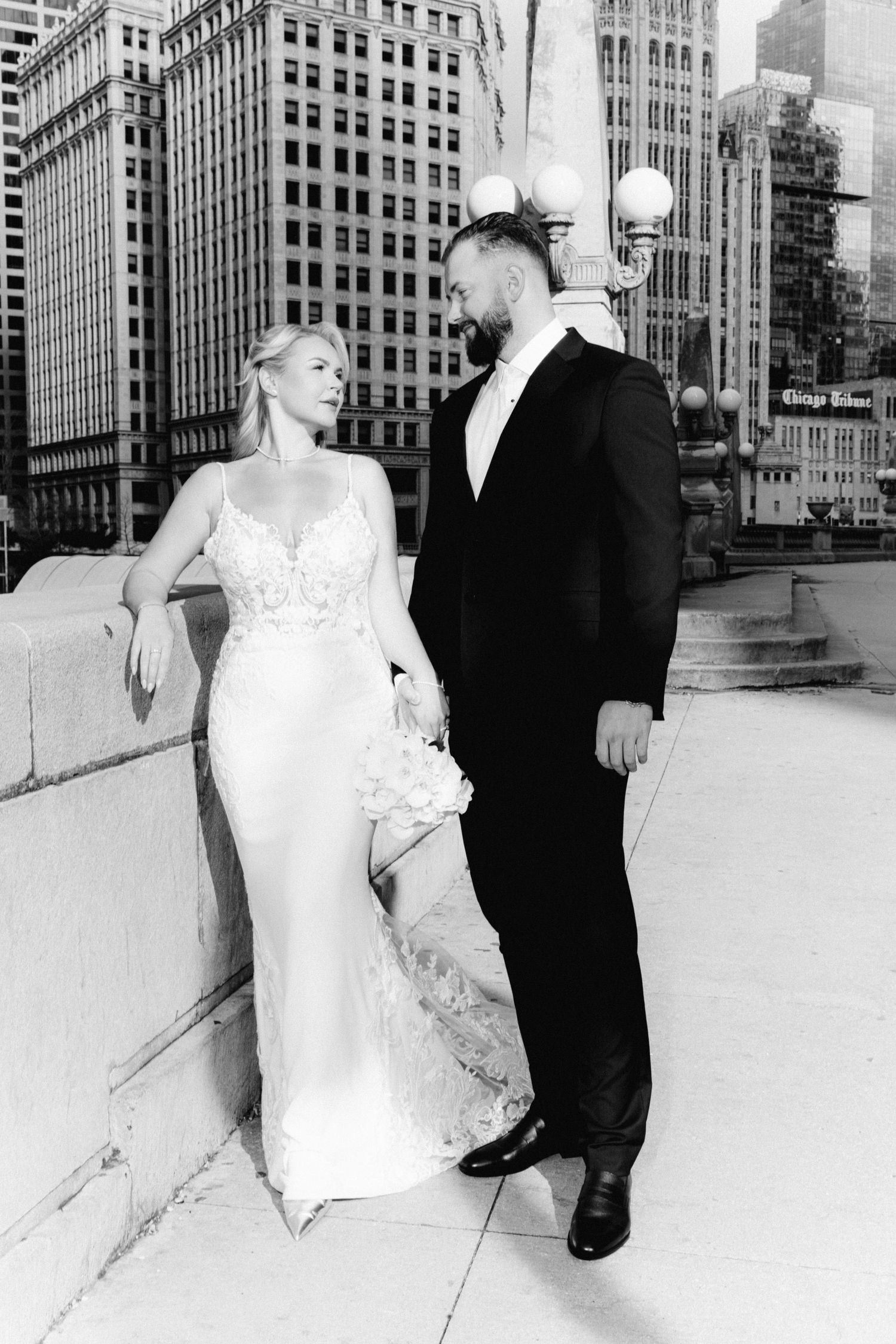 Black and white wedding portrait of couple on Chicago bridge with skyscrapers in background.