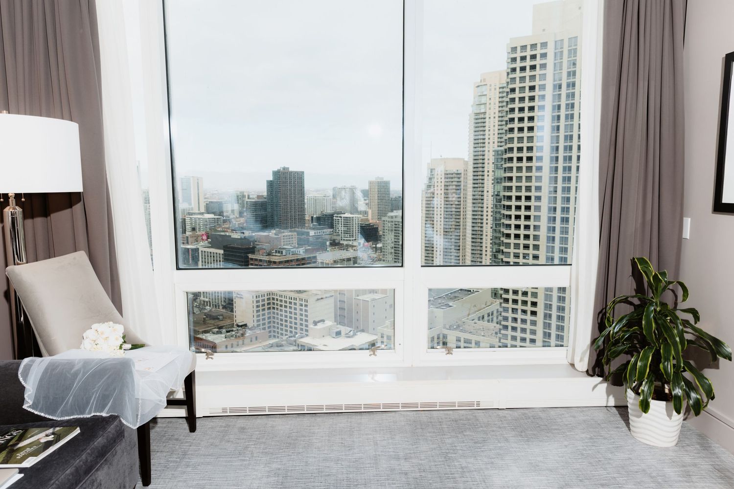 Modern hotel room with floor-to-ceiling windows overlooking Chicago city skyline and skyscrapers.