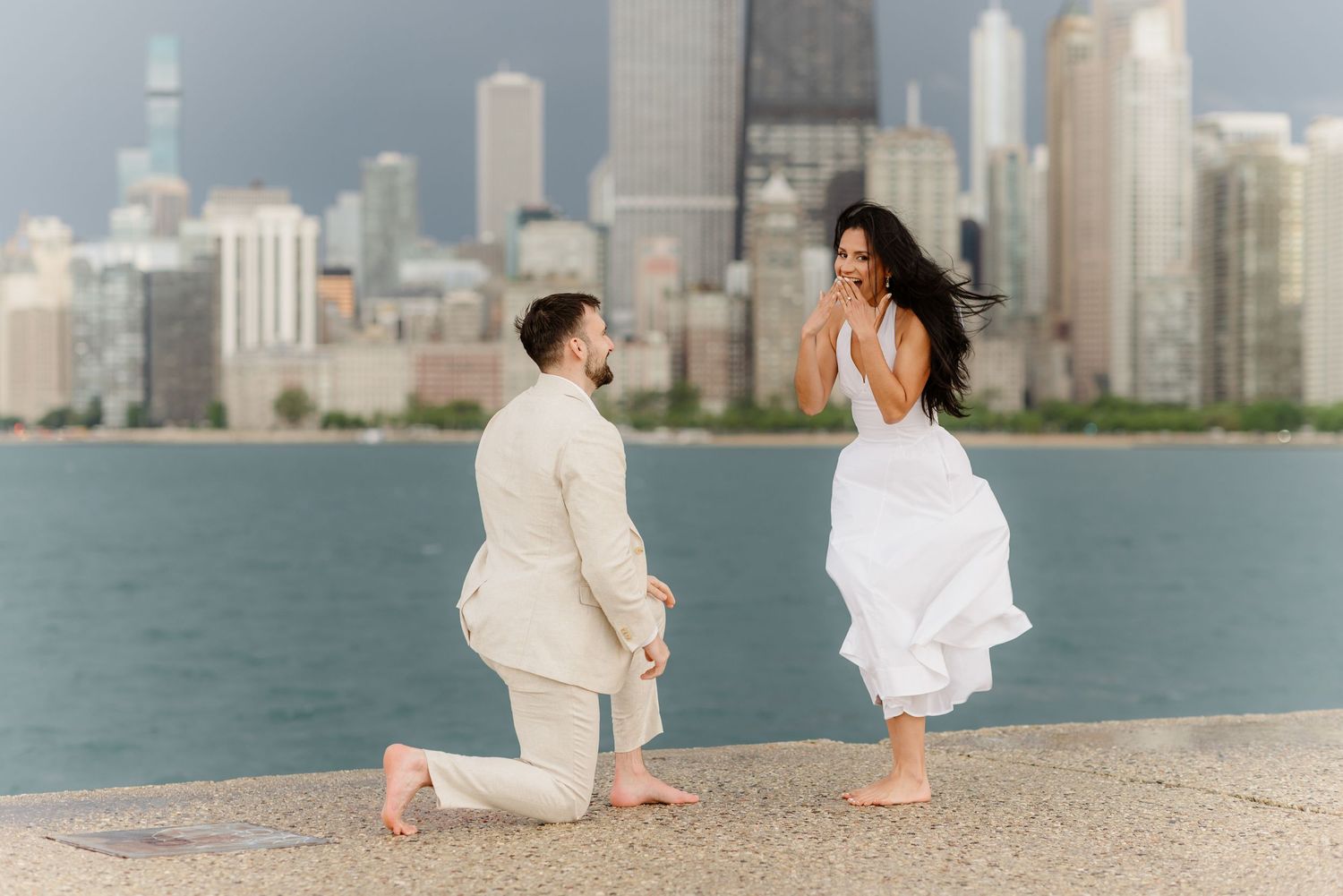 Romantic marriage proposal on Chicago lakefront pier with stunning city skyline in the background.