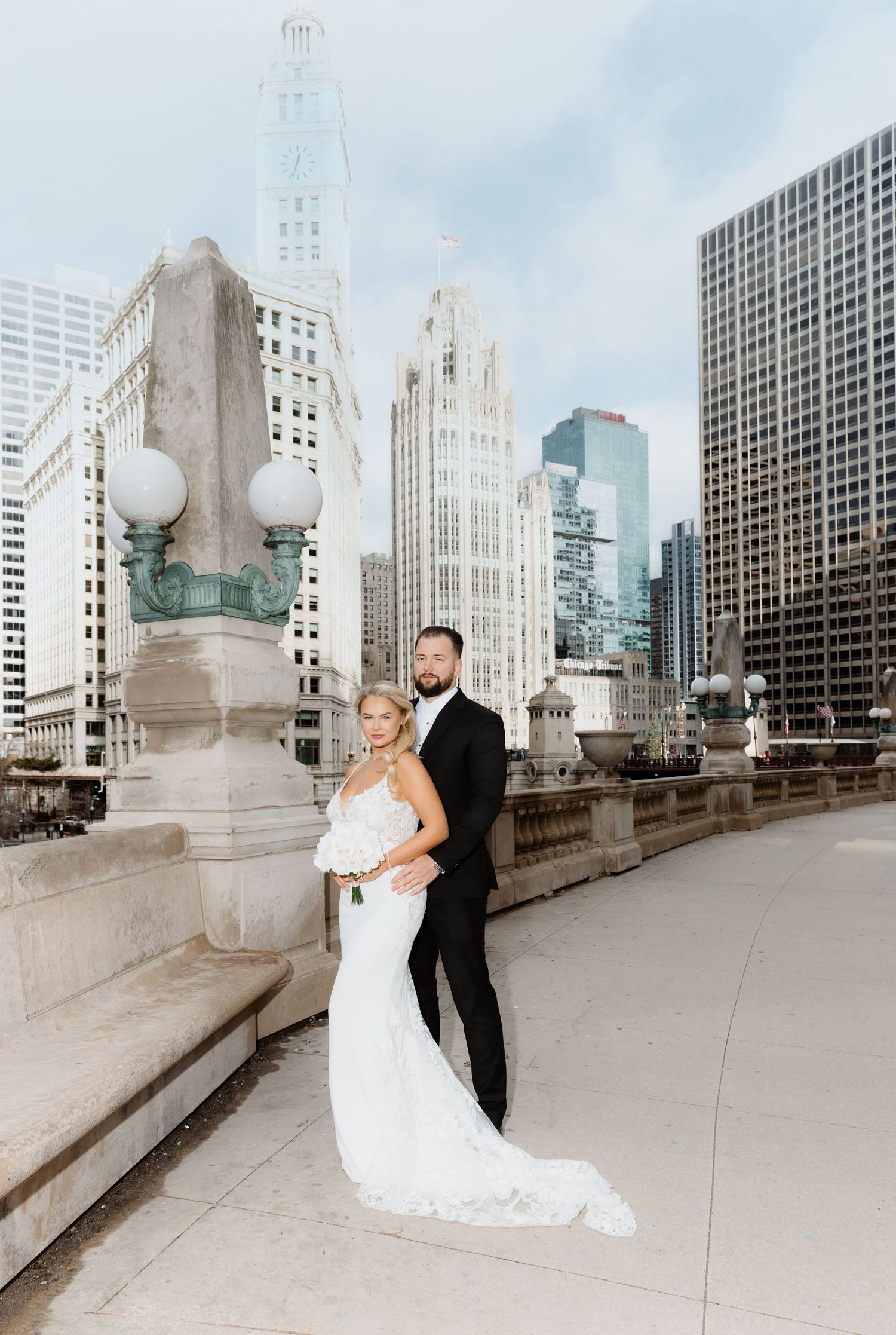 Elegant bride and groom posing on Chicago's DuSable Bridge with Tribune Tower in background.