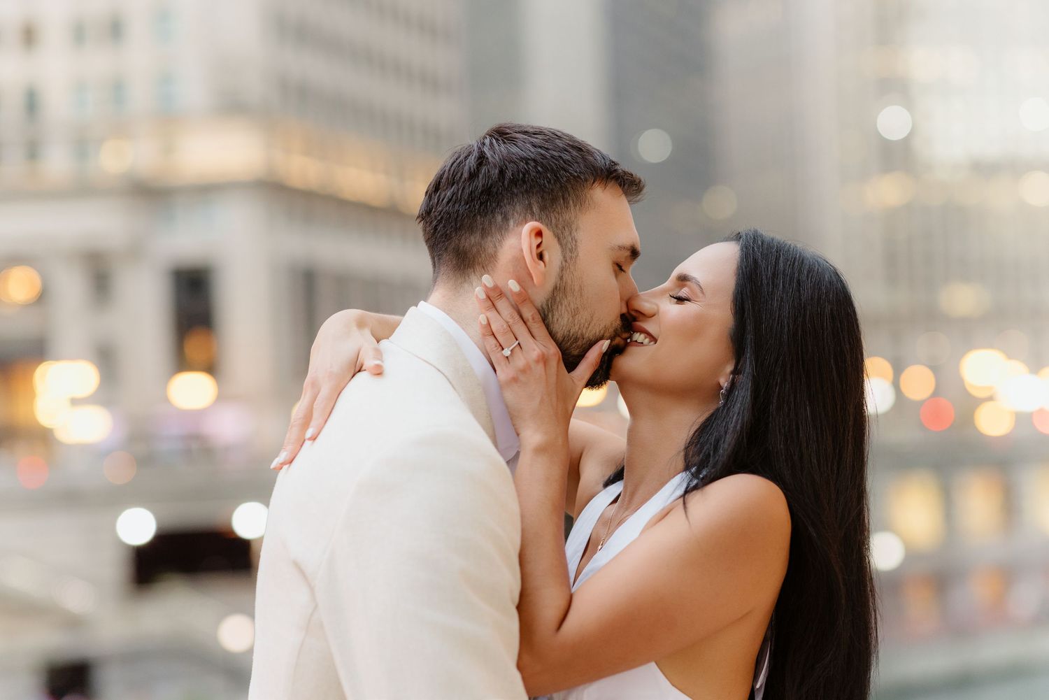 Close-up of couple kissing with bokeh city lights behind them during Chicago engagement photo session.