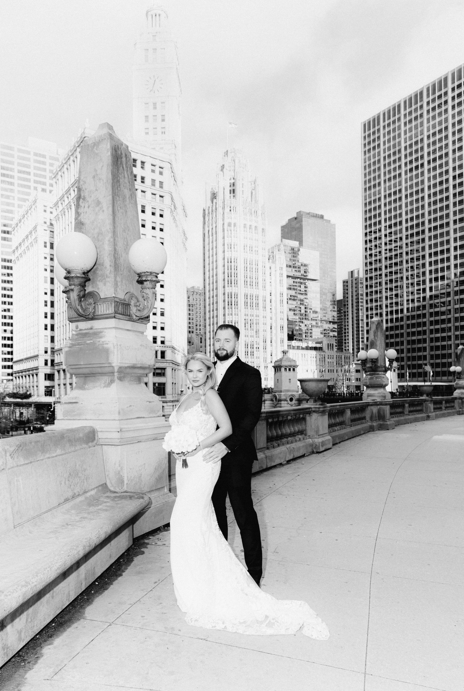 Black and white wedding portrait of couple embracing on Chicago bridge with city skyline.