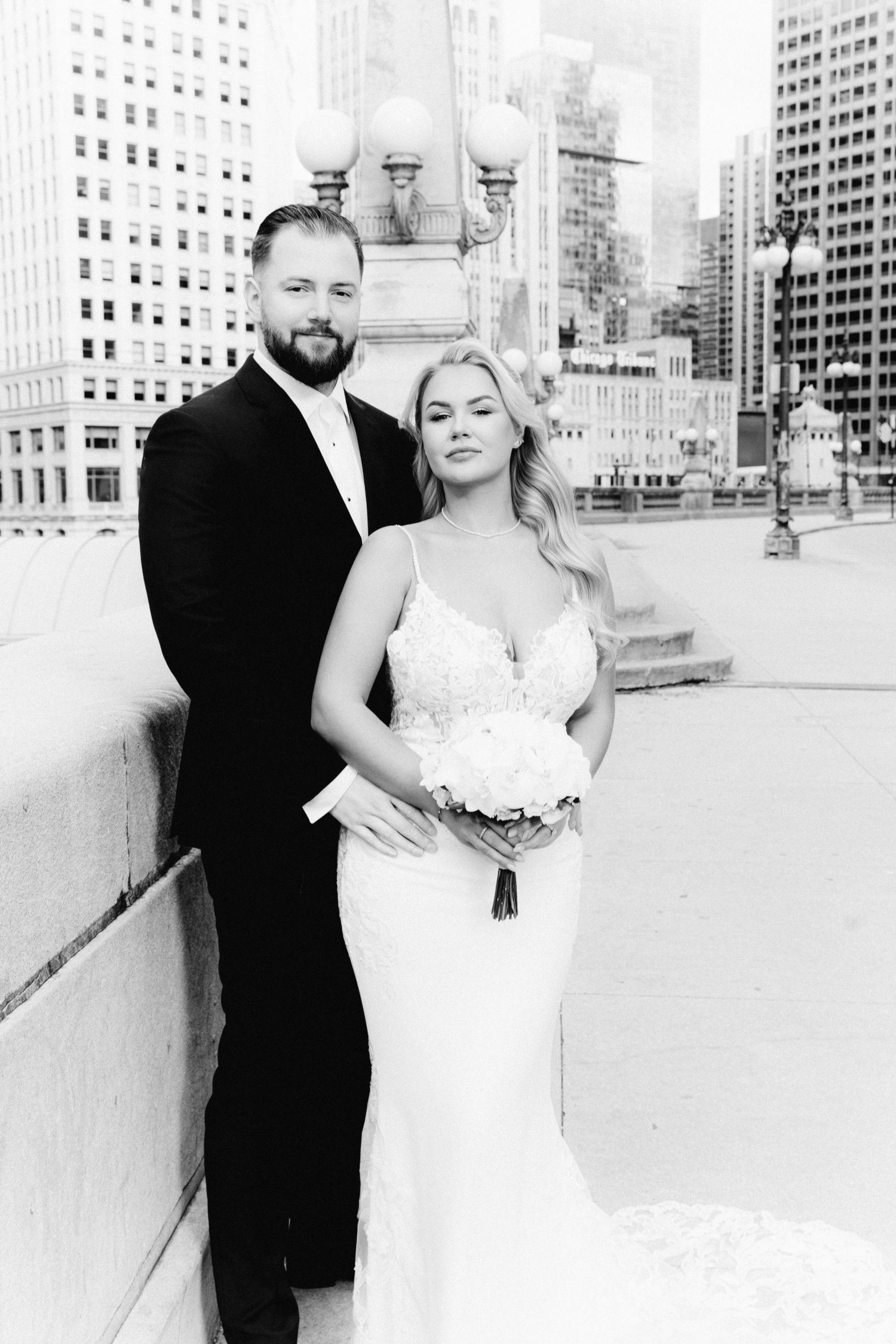 Elegant black and white wedding portrait of couple on Chicago bridge surrounded by towering city buildings.