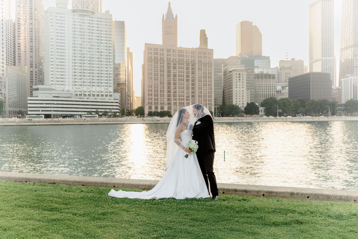 Bride and groom kissing at golden hour with Chicago skyline backdrop.
