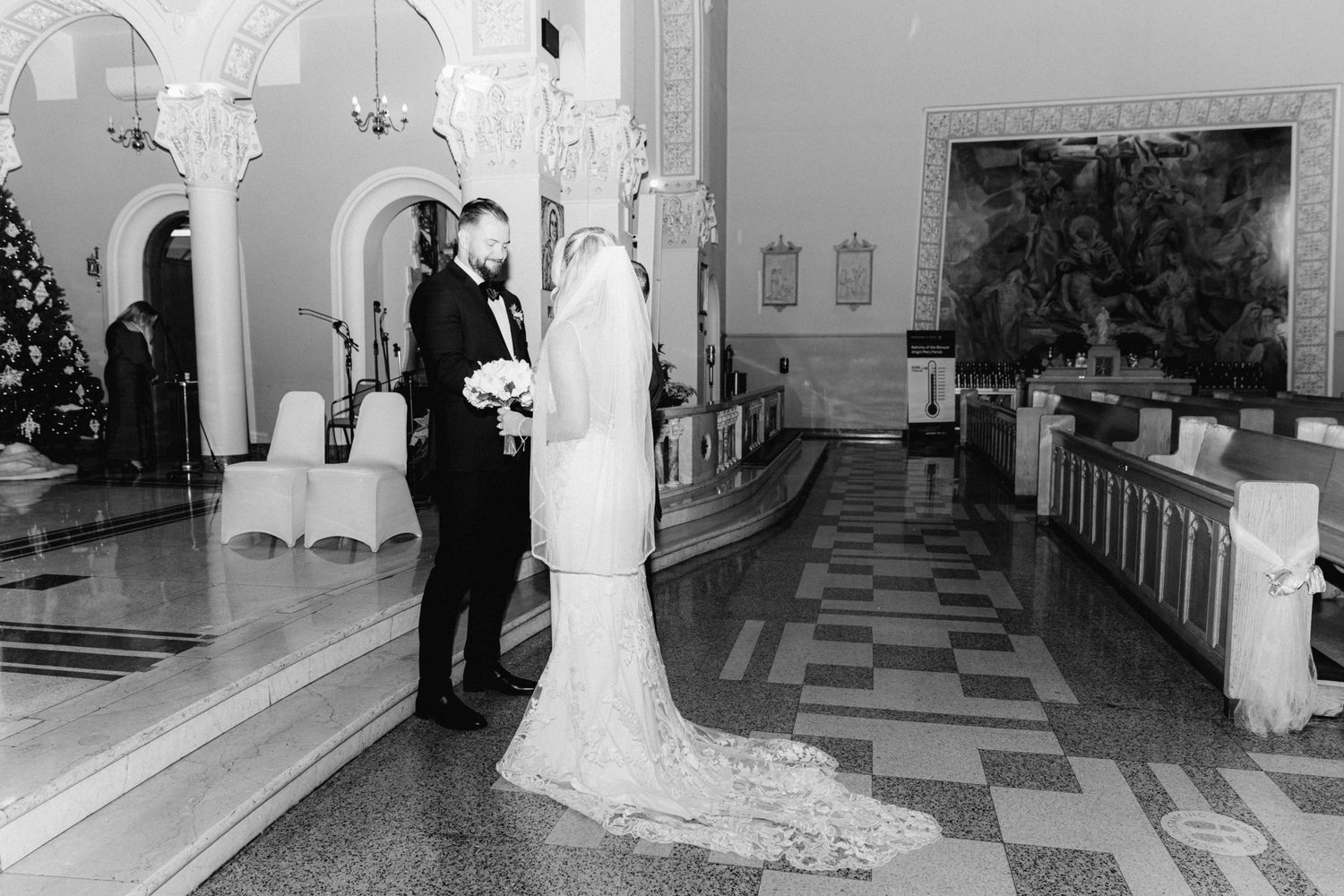 Black and white photo of bride and groom sharing first look in elegant church hall.
