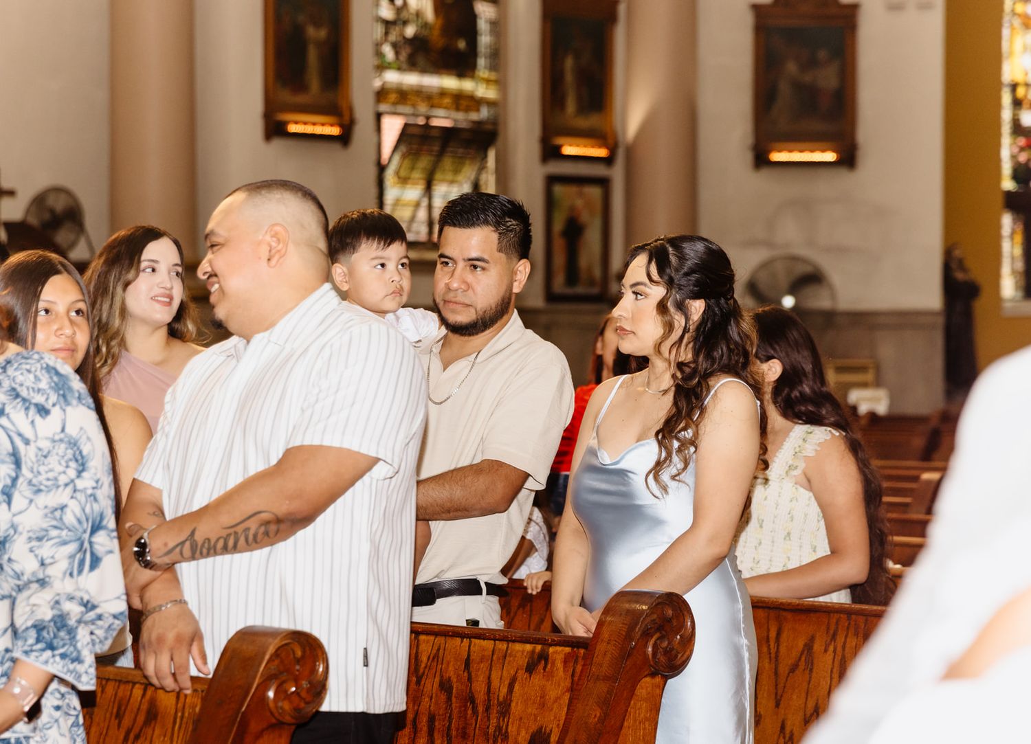 Group of elegantly dressed guests standing in a beautiful church during a wedding ceremony.