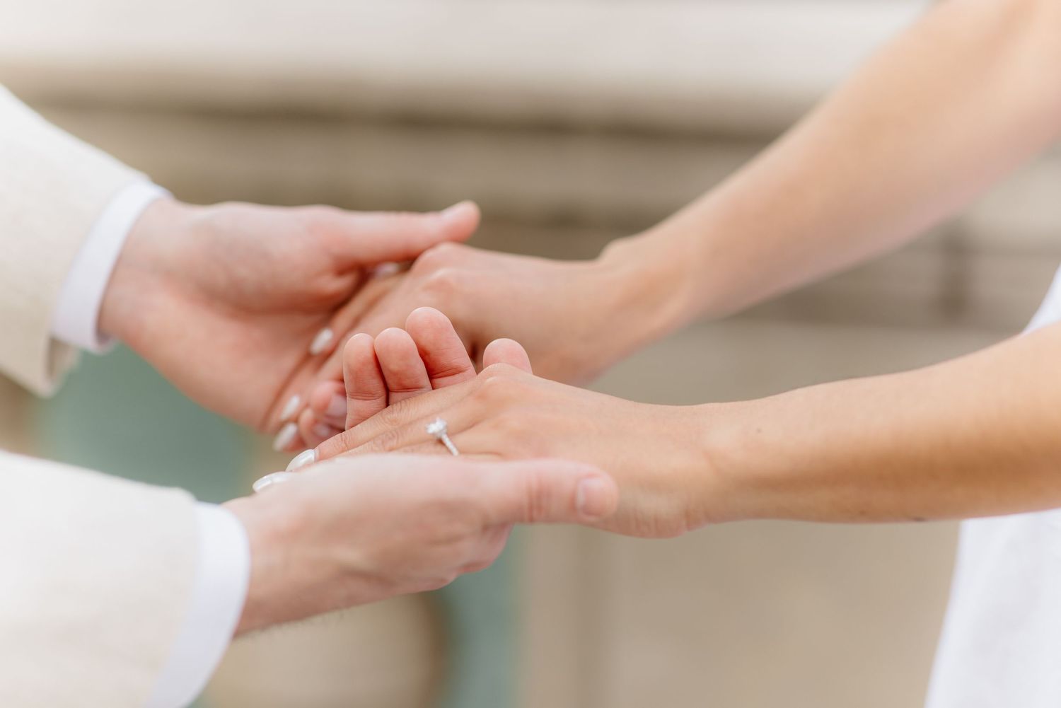 Close-up of hands exchanging wedding rings during outdoor ceremony.