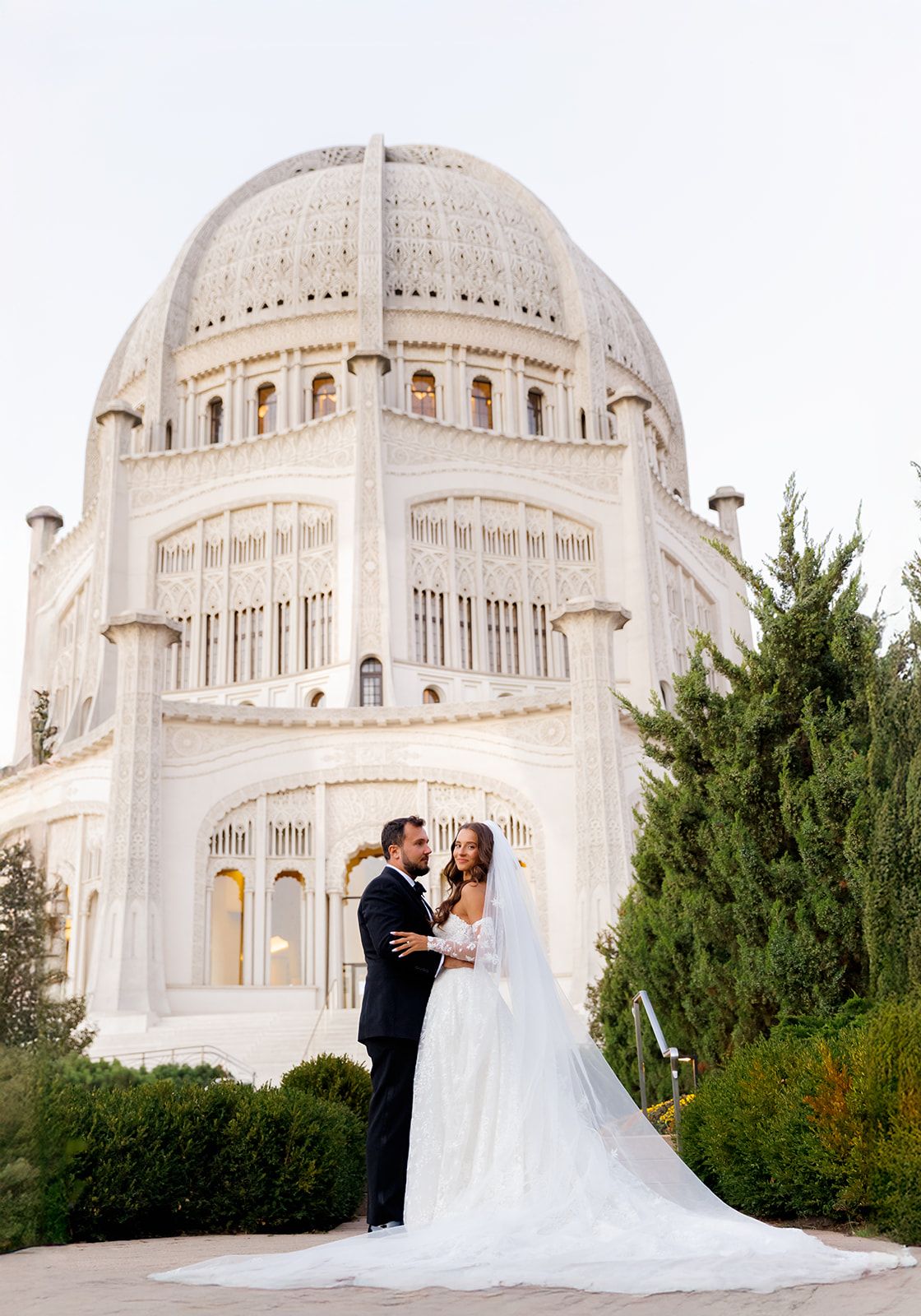 Bride and groom pose before the ornate white Bahai Temple dome in Wilmette, Illinois on their wedding day.