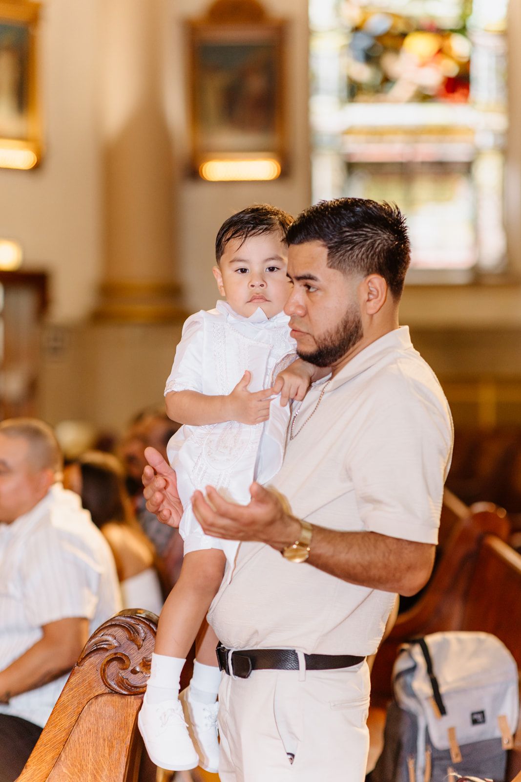 A father holds his baby dressed in white during a church baptism ceremony.
