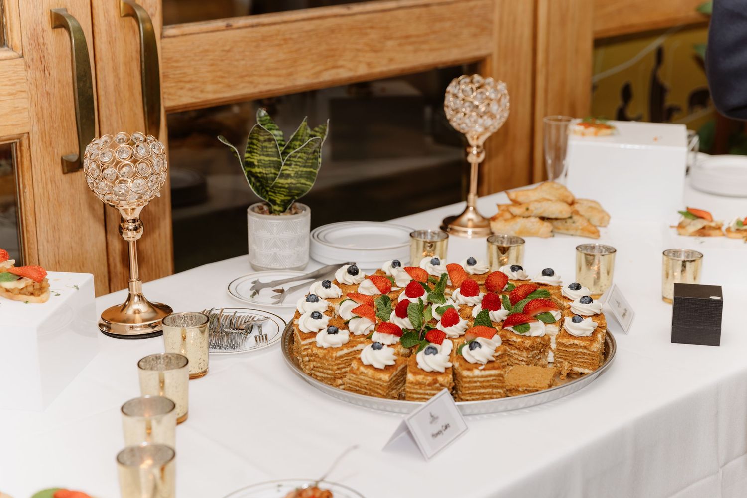 Elegant wedding reception dessert table with pastries topped with fresh fruit.