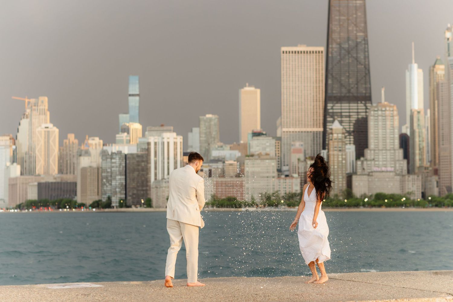 Romantic couple walking barefoot along Chicago lakefront with stunning city skyline view.