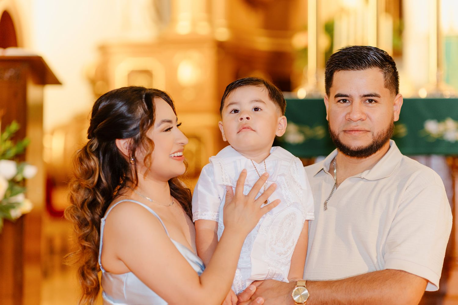 A happy family poses together at a baptism ceremony inside a church.