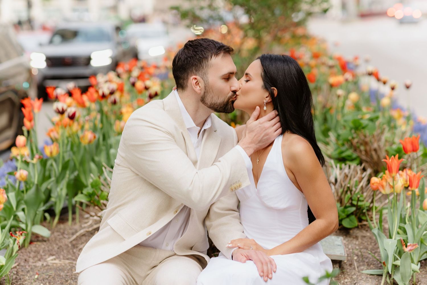 Couple sharing romantic kiss surrounded by vibrant tulips in Chicago street garden.