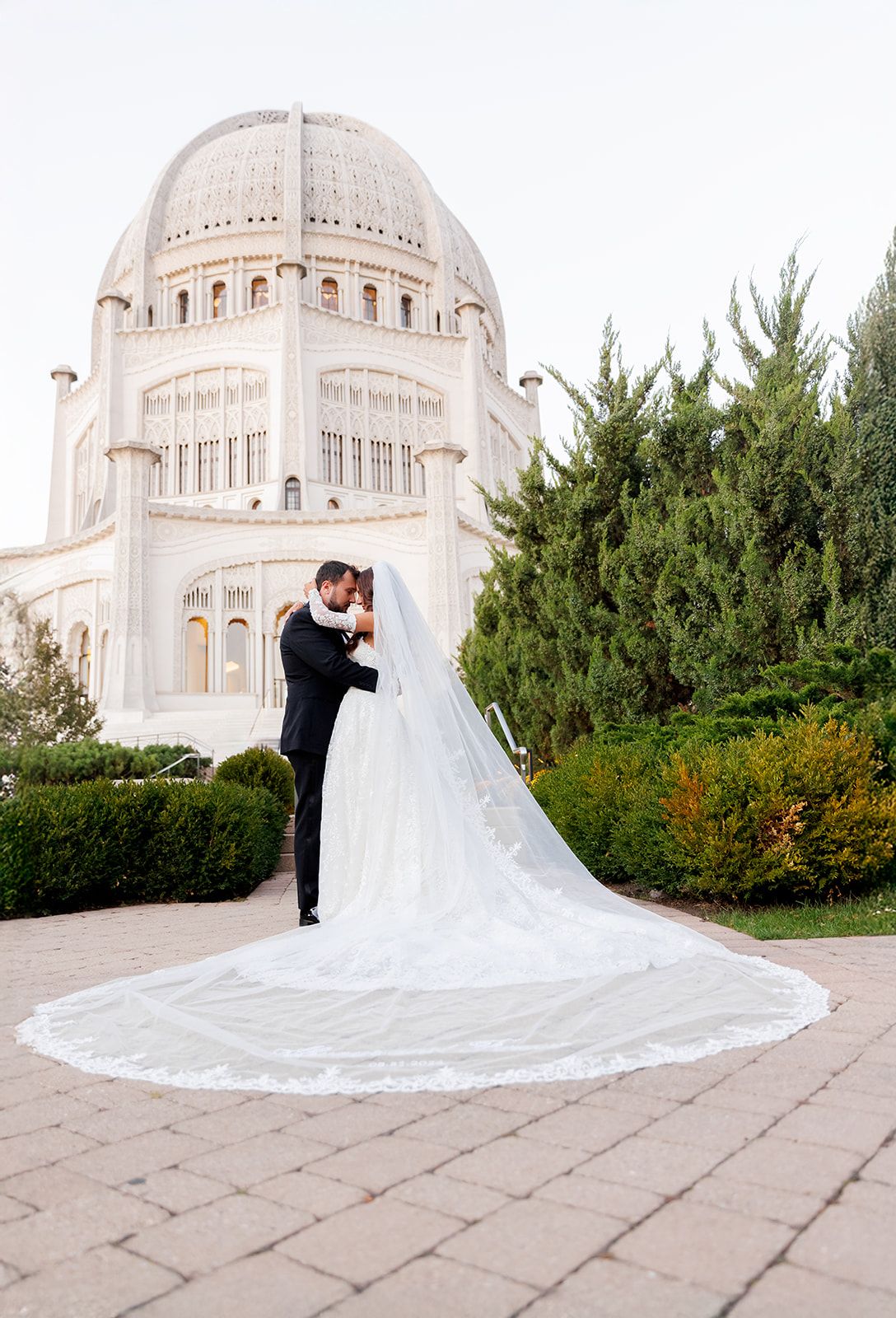 Bride and groom share a romantic kiss outside the Bahai Temple in Wilmette, Illinois, with a dramatic cathedral veil.