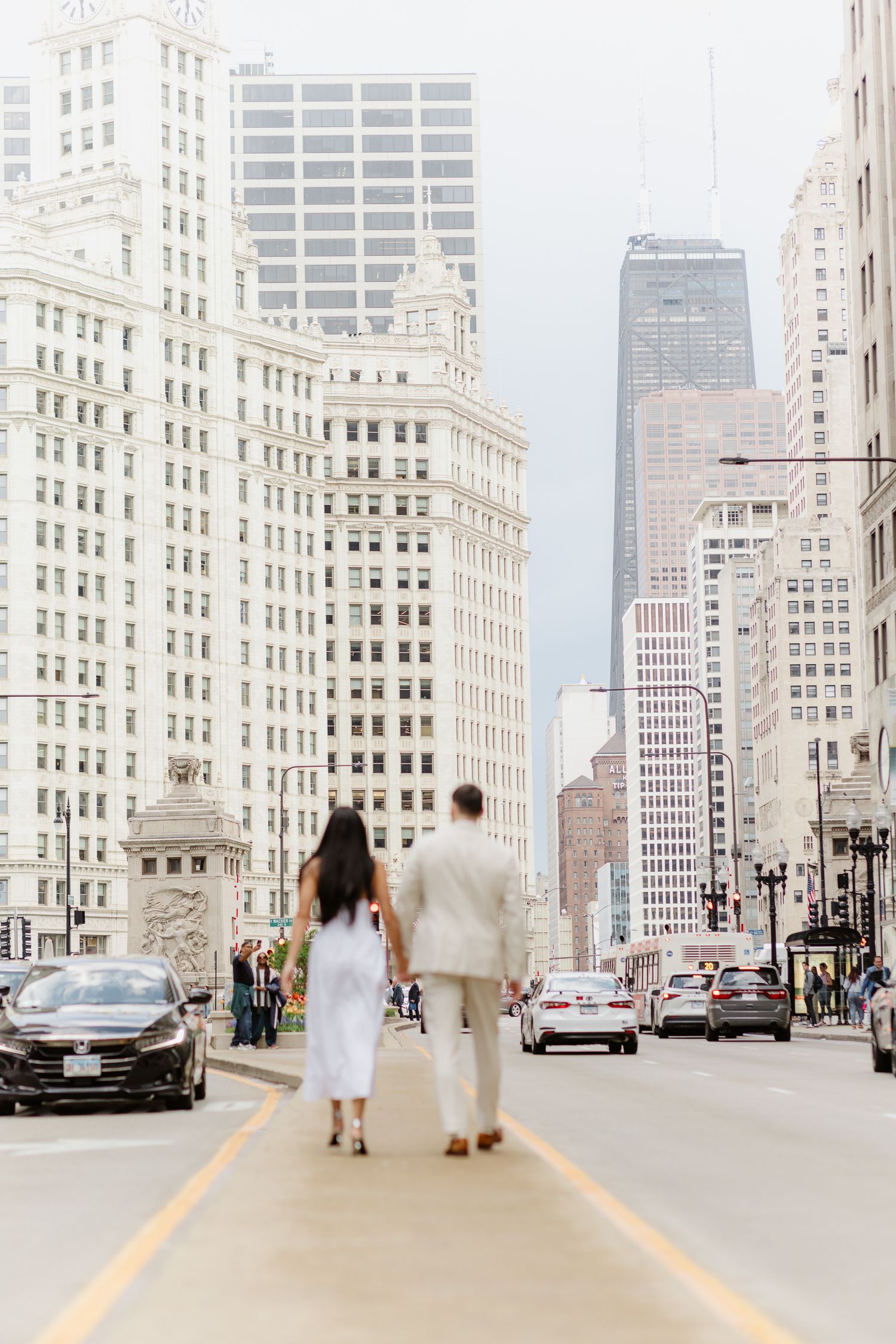 Couple walks hand-in-hand down Chicago's Michigan Avenue surrounded by iconic city skyscrapers.