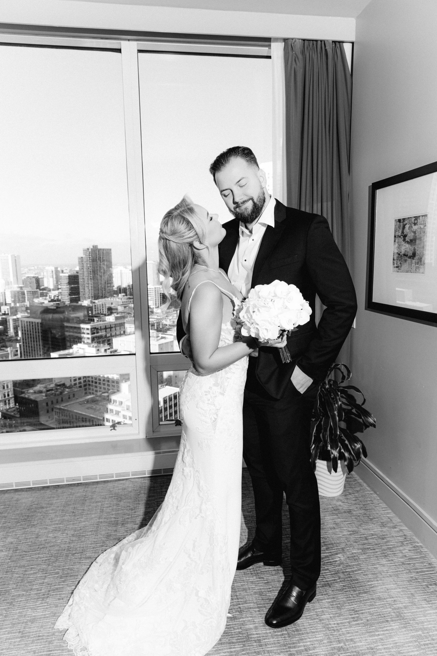 Black and white photo of a bride and groom sharing a tender moment in a hotel room.